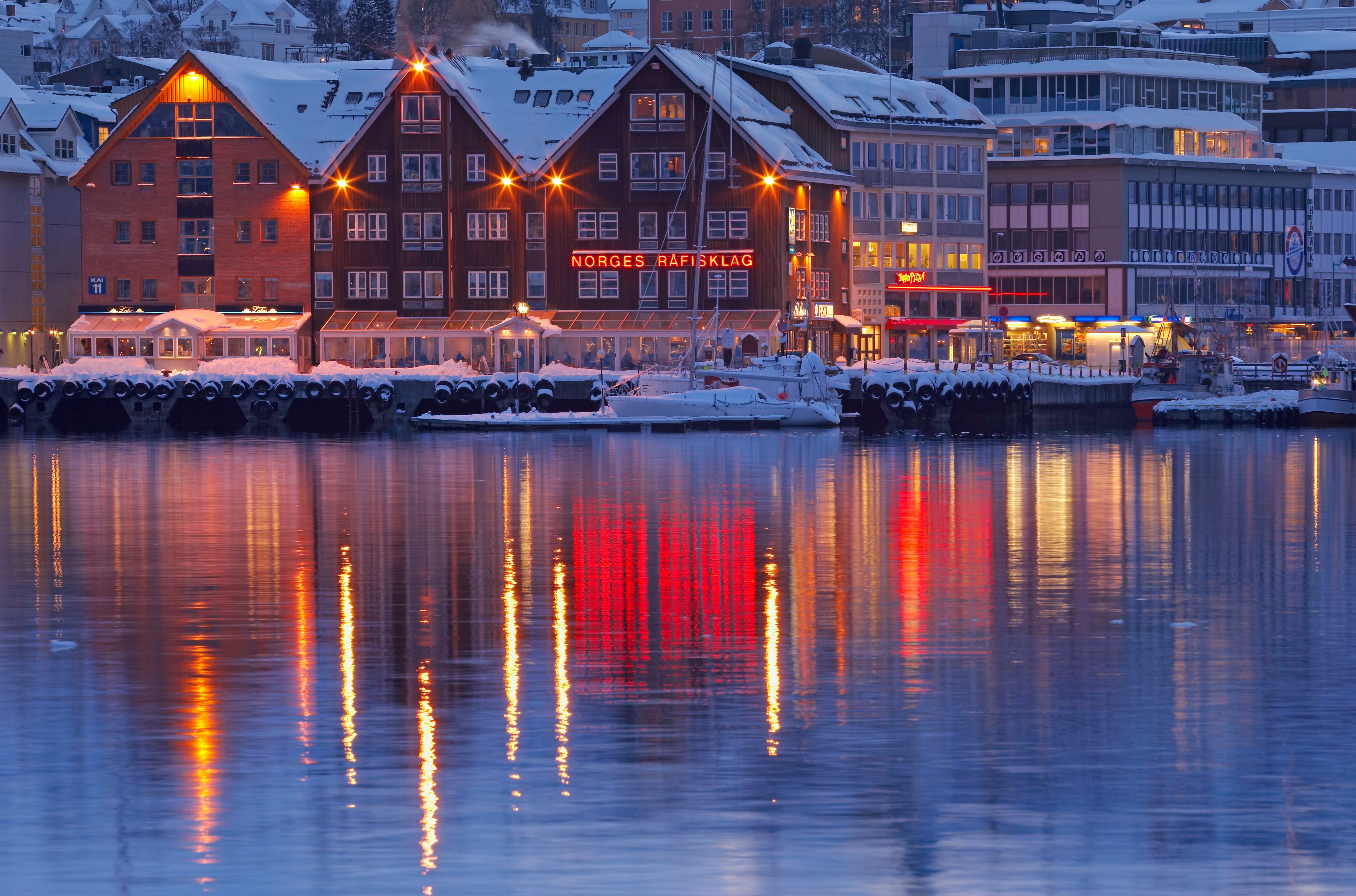 Warme Lichter, die sich auf ruhigem Wasser während der arktischen Polarnacht spiegeln