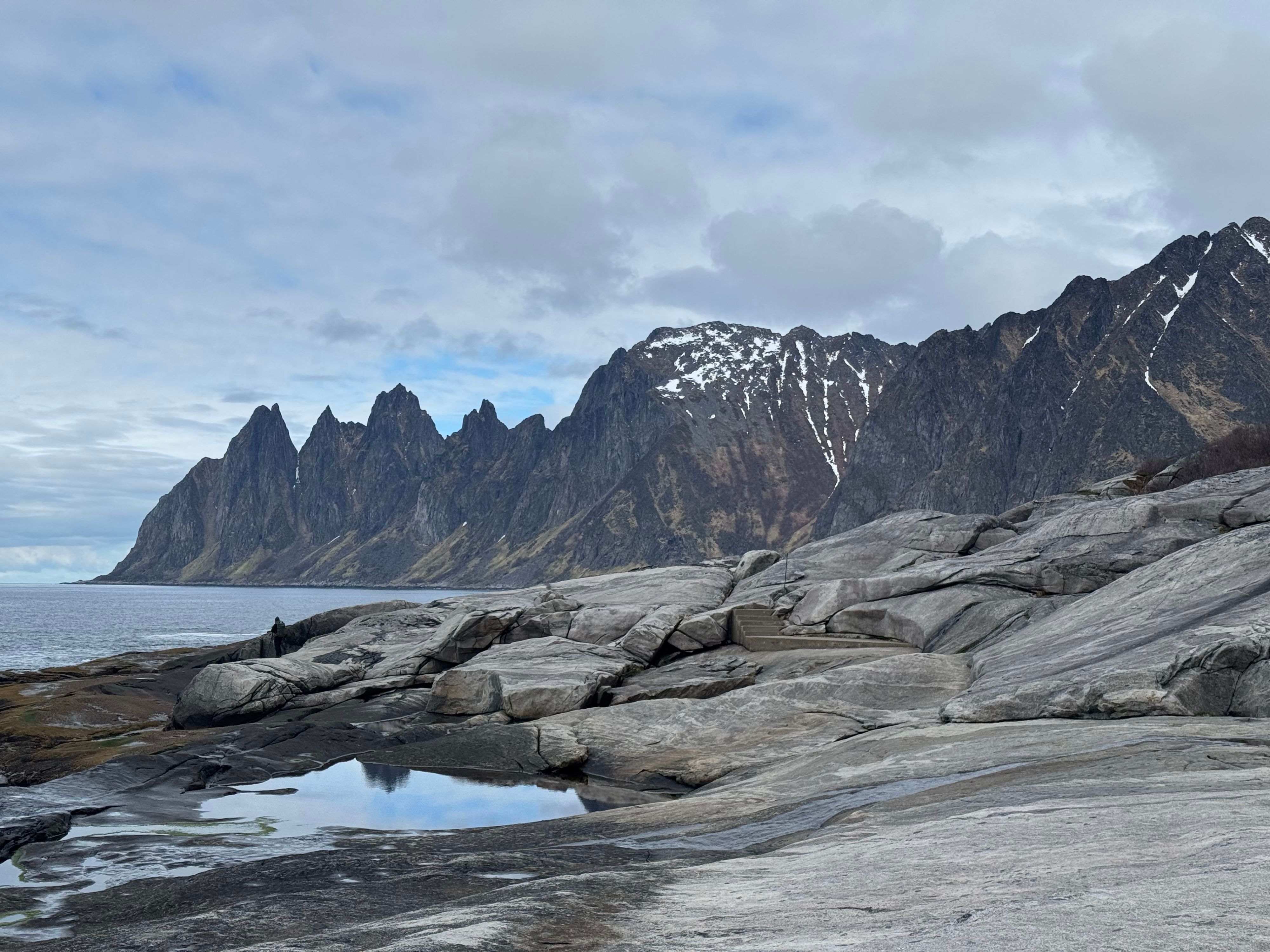 Den ikoniske Tungeneset-bryggen med utsikt over de taggete Okshornan-toppene langs Nasjonal turistveg Senja i Nord-Norge.