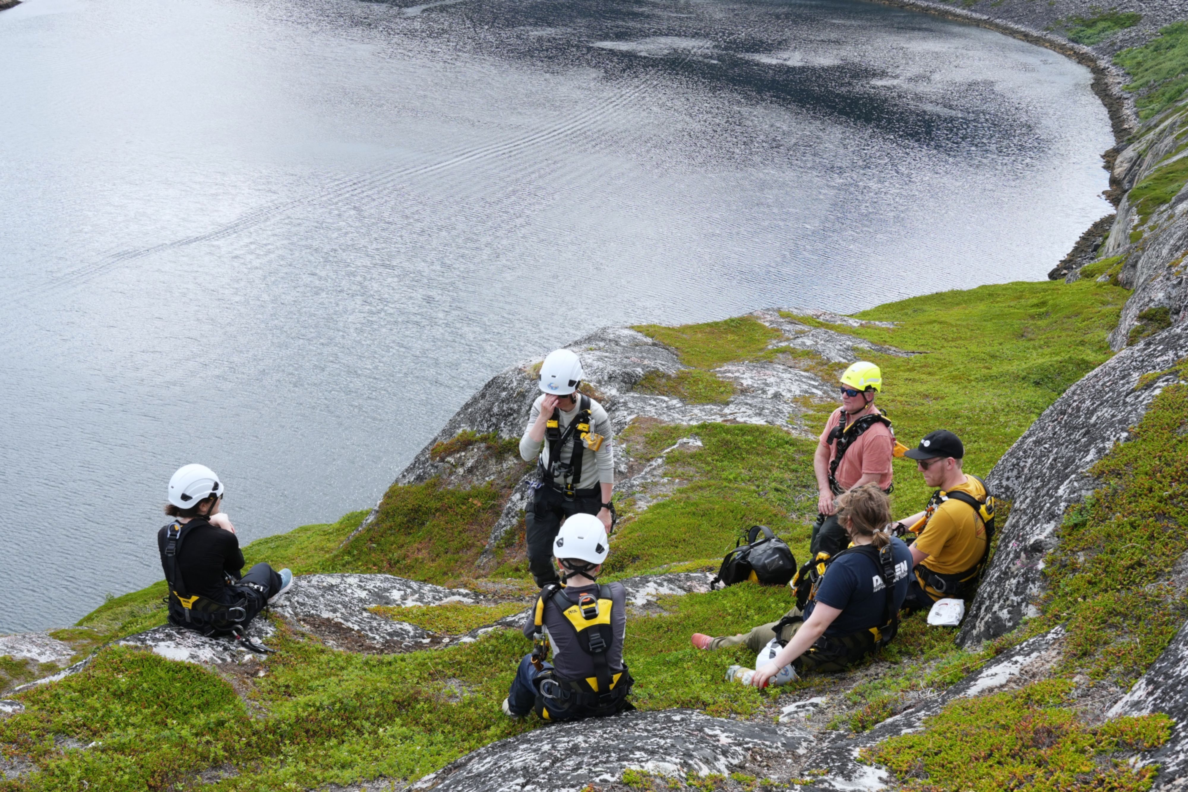 Participants receiving a safety briefing before the Arctic Rappelling Route on a coastal cliff in Northern Norway.