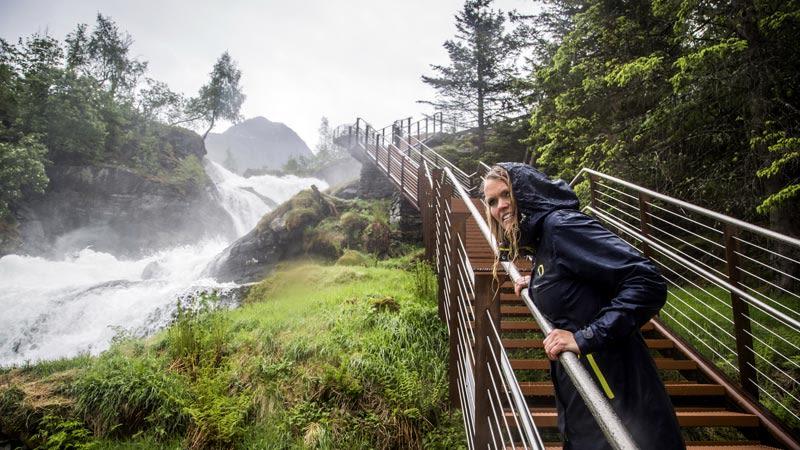 Ein Gast spaziert neben einem Wasserfall in Geiranger, Norwegen