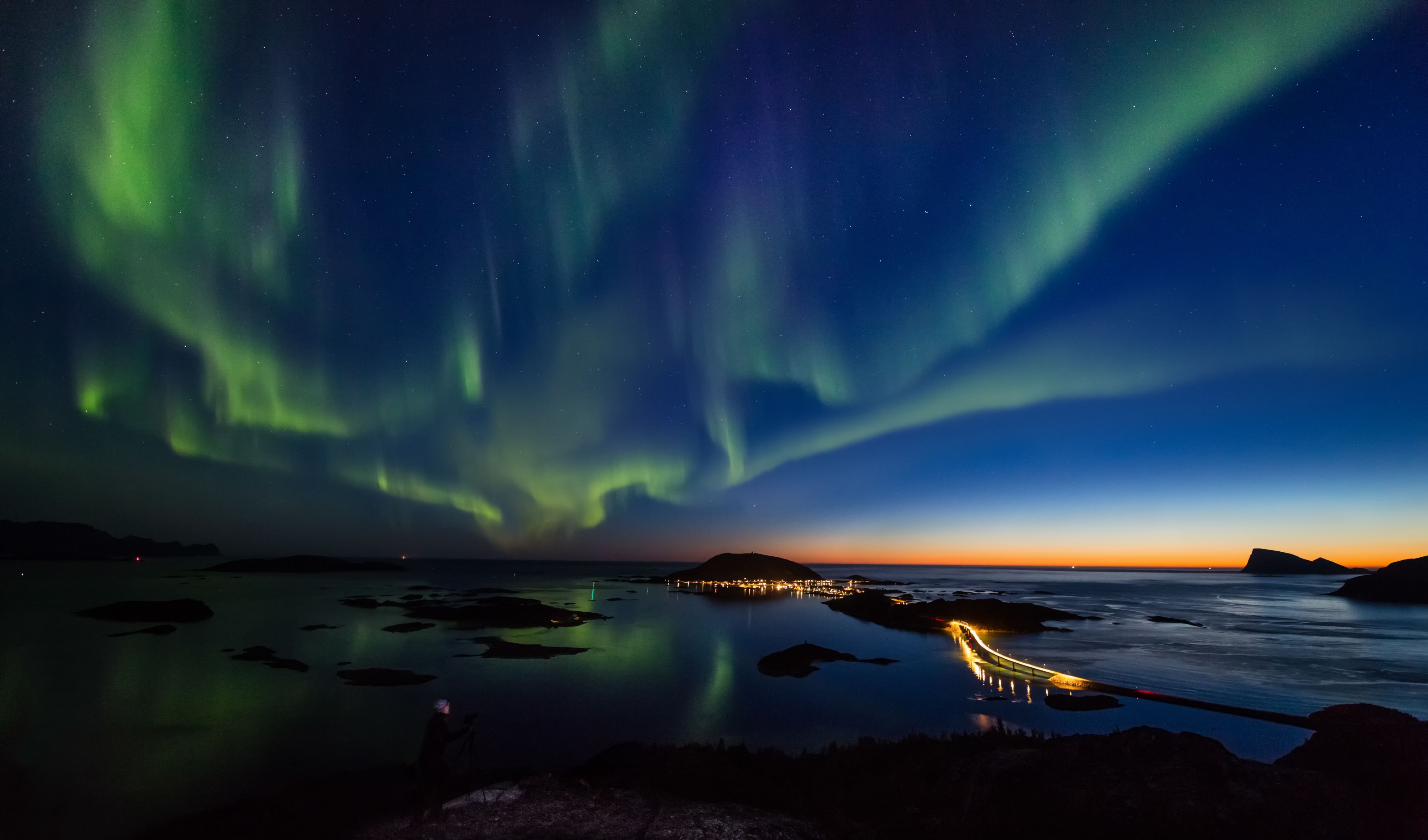 Nordlys som danser over et kystlandskap og en opplyst bro på Lofoten, høst, Norge