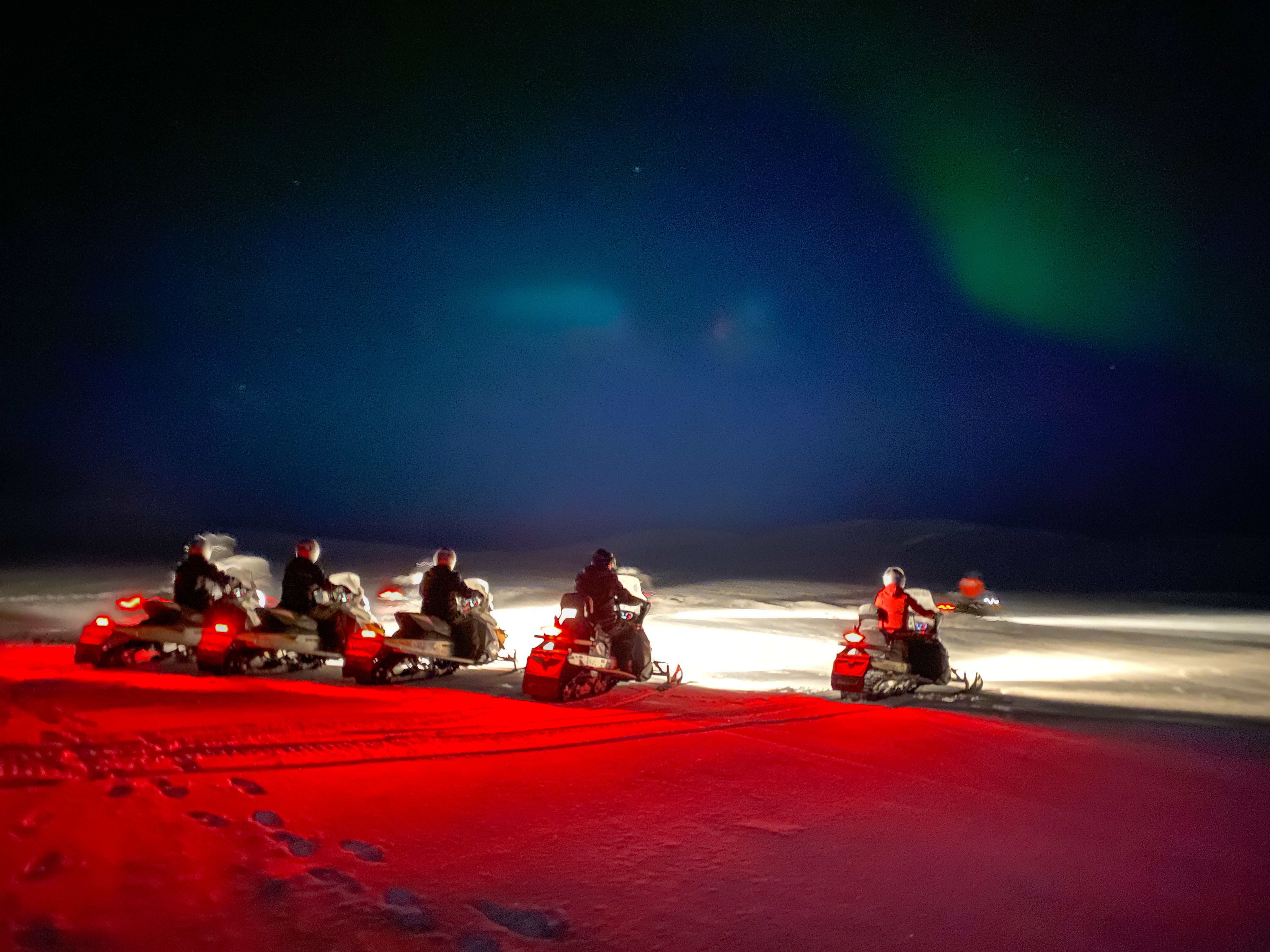 Group of snow mobile drivers in the polar night