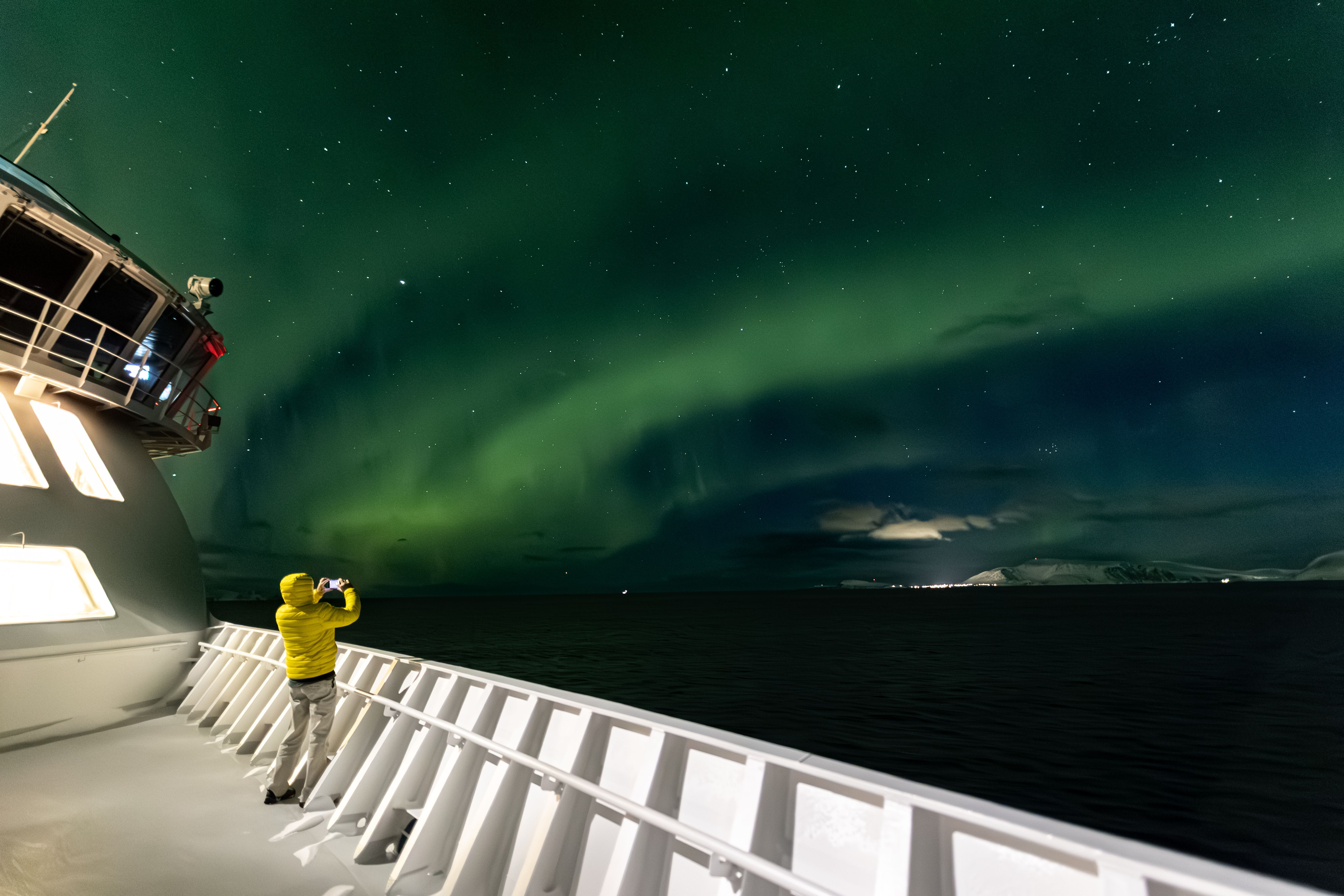 Gäst som fotograferar norrskenet från däcket på ett av Havila Kystrutens fartyg