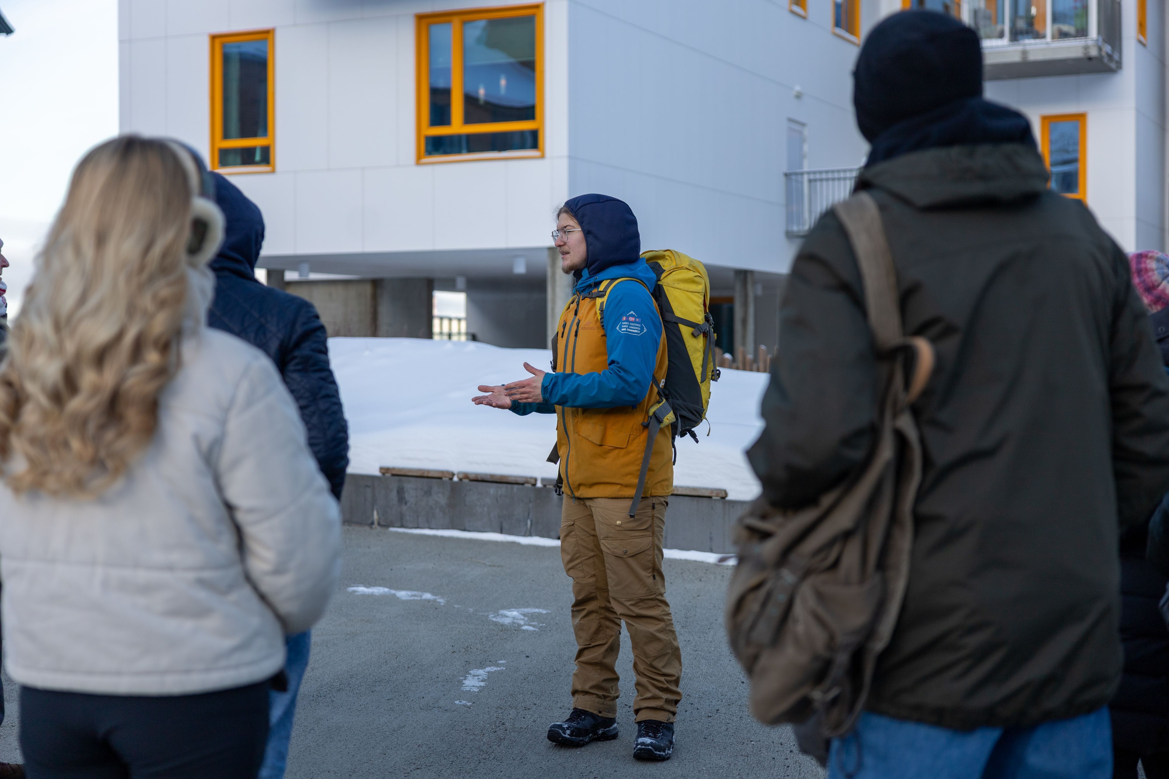 Guide i gul jacka som talar till en grupp besökare under en vinterstadsvandring i Hammerfest, Norge