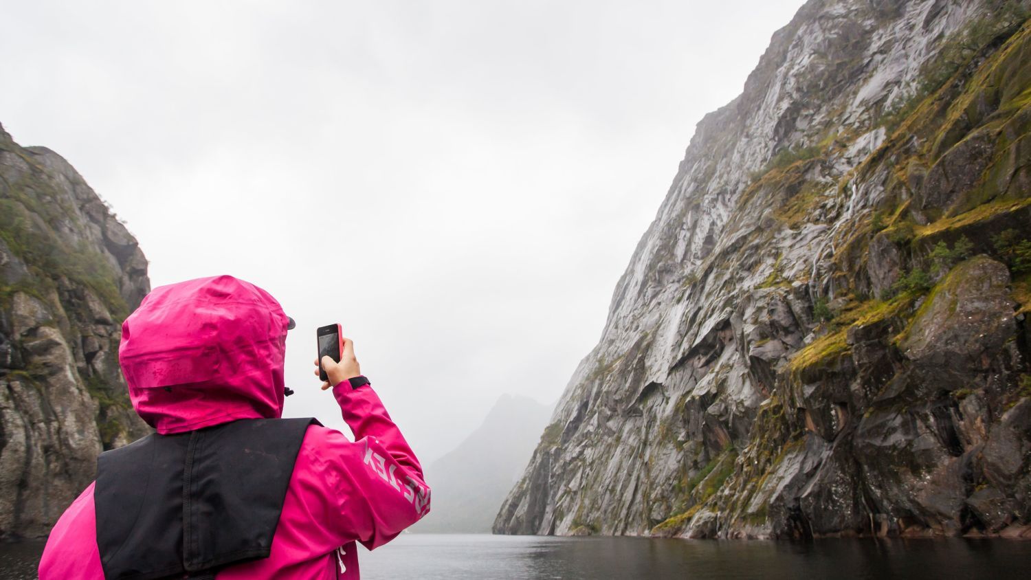 Besucher fotografiert die hoch aufragenden Granitklippen des Trollfjords von einem Boot in Nordnorwegen aus.