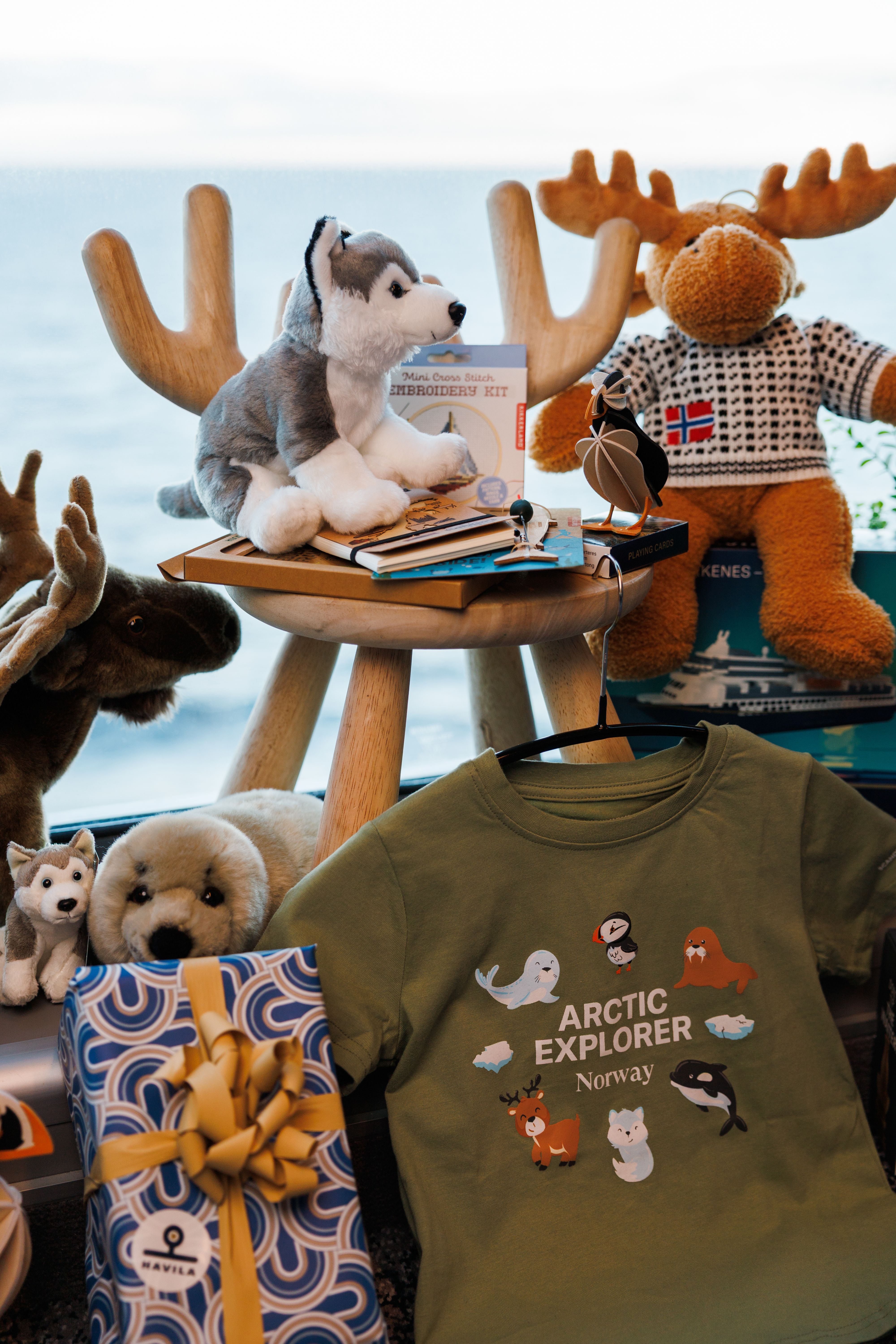 Arktis-inspirierte Souvenirs im Bordshop von Havila Kystruten, darunter Plüschtiere, Kinderkleidung, norwegische Geschenkartikel und Reisesouvenirs, die von der norwegischen Küste inspiriert sind.