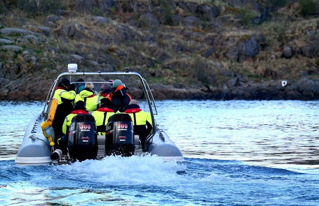Gjester om bord i en RIB-båt som utforsker kystlinjen ved Henningsvær i Lofoten.