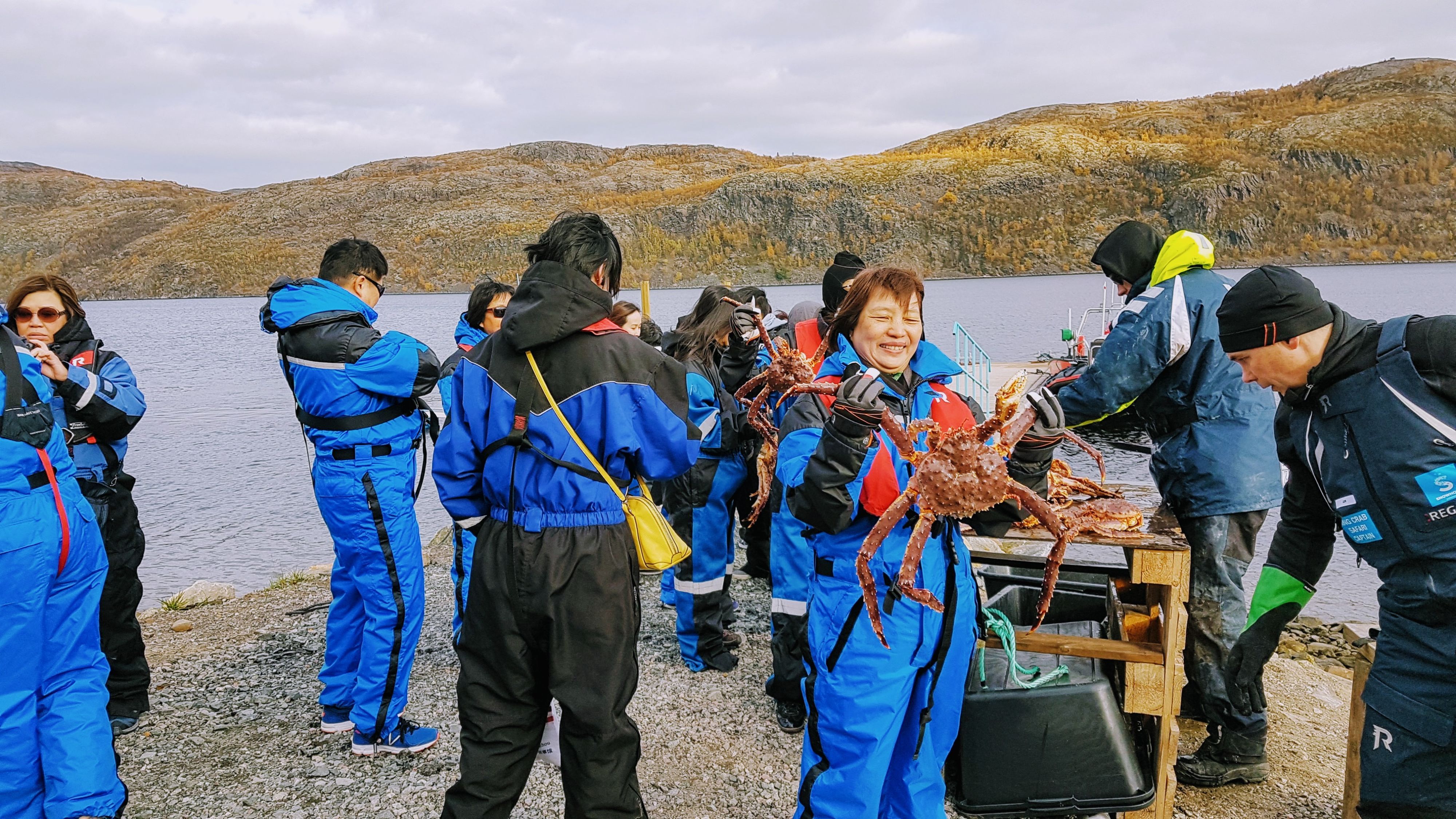 Gjester på en kongekrabbsafari med Havila Voyages i Kirkenes holder nyfanget kongekrabbe under en bærekraftig arktisk utflukt langs kysten i Nord-Norge.