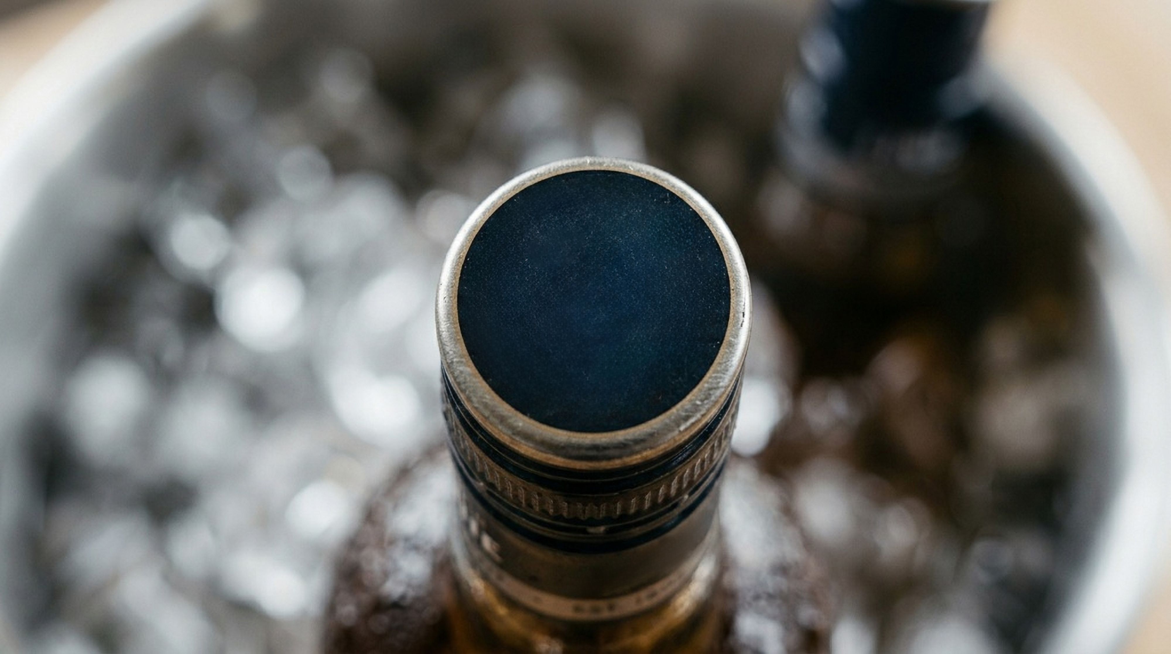 Close-up of a bottle neck in an ice bucket, seen from above