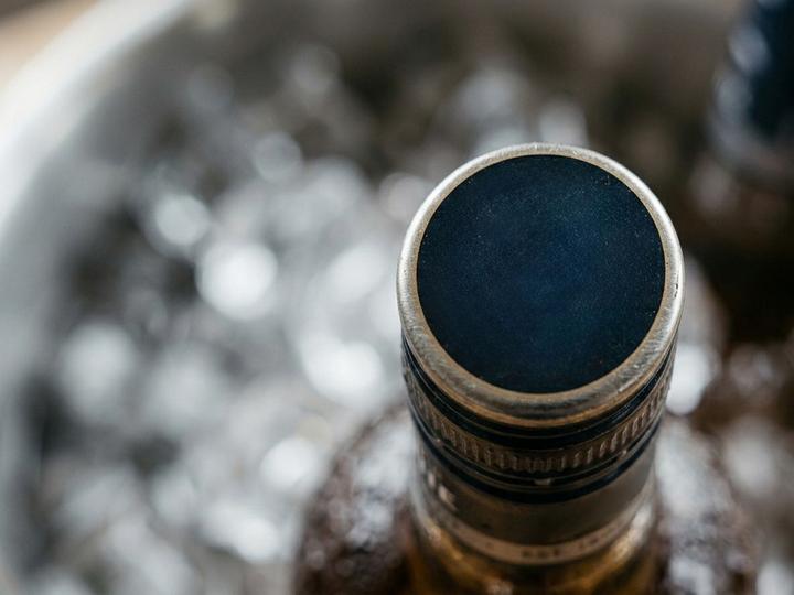 Close-up of a bottle neck in an ice bucket, seen from above