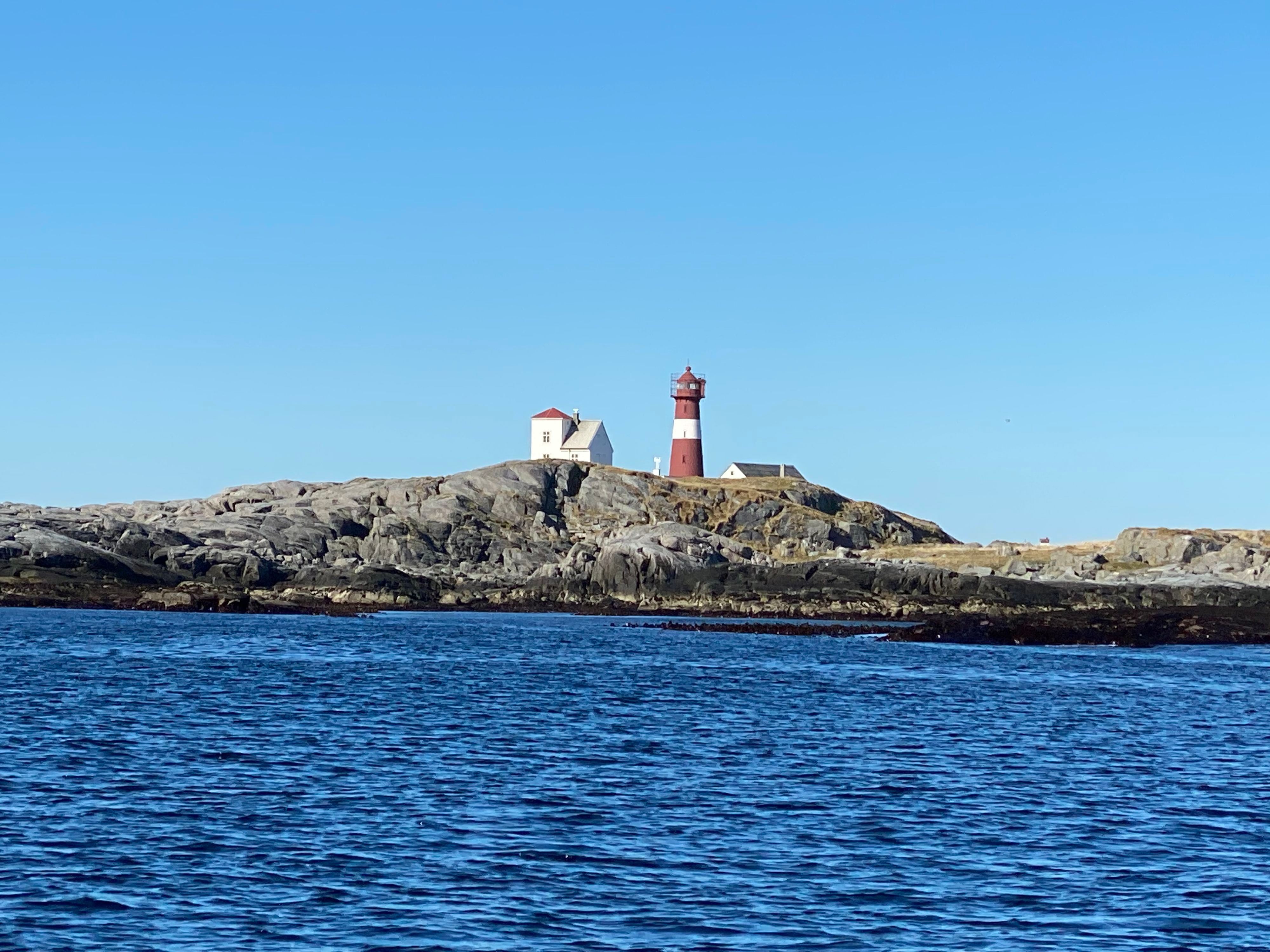 Grasøyane Lighthouse on a remote rocky island off the coast of Norway, overlooking the open sea and dramatic coastal landscape