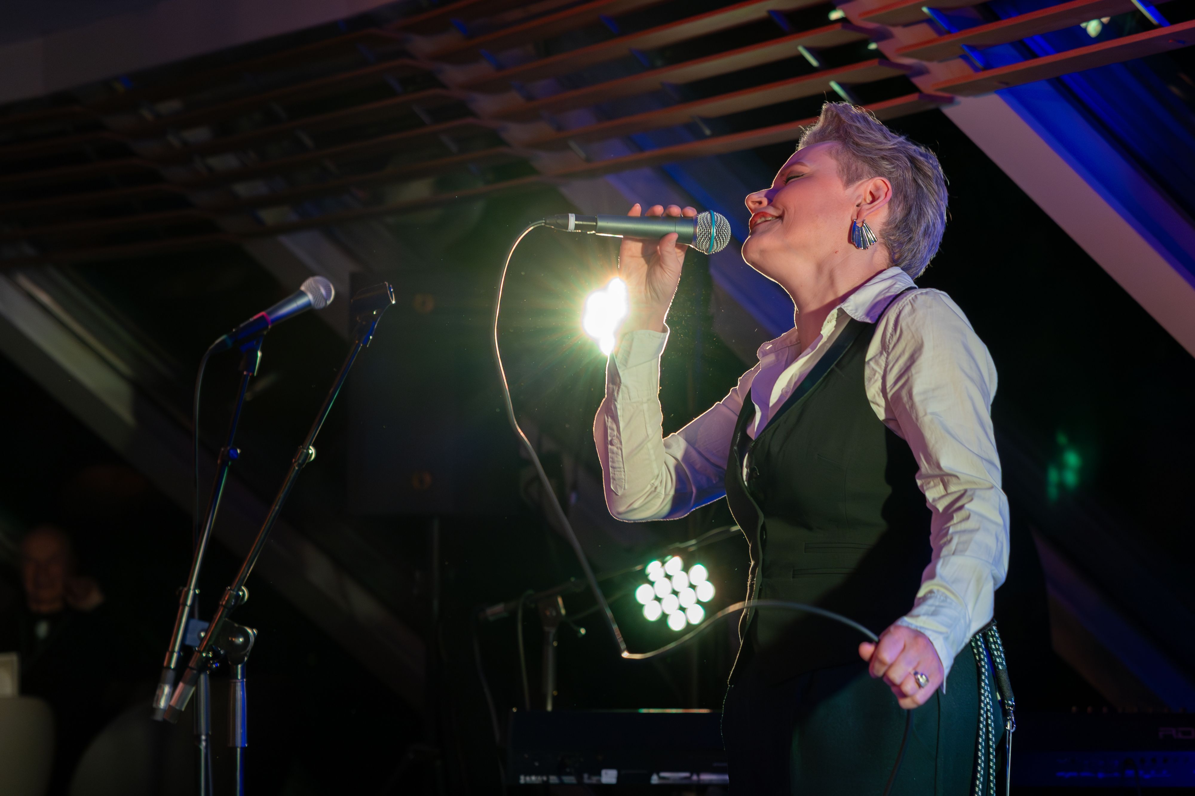 Stina Stenerud opptrer live om bord på Havila Voyages Blues Cruise 2027, og synger på scenen under fargerik konsertbelysning.