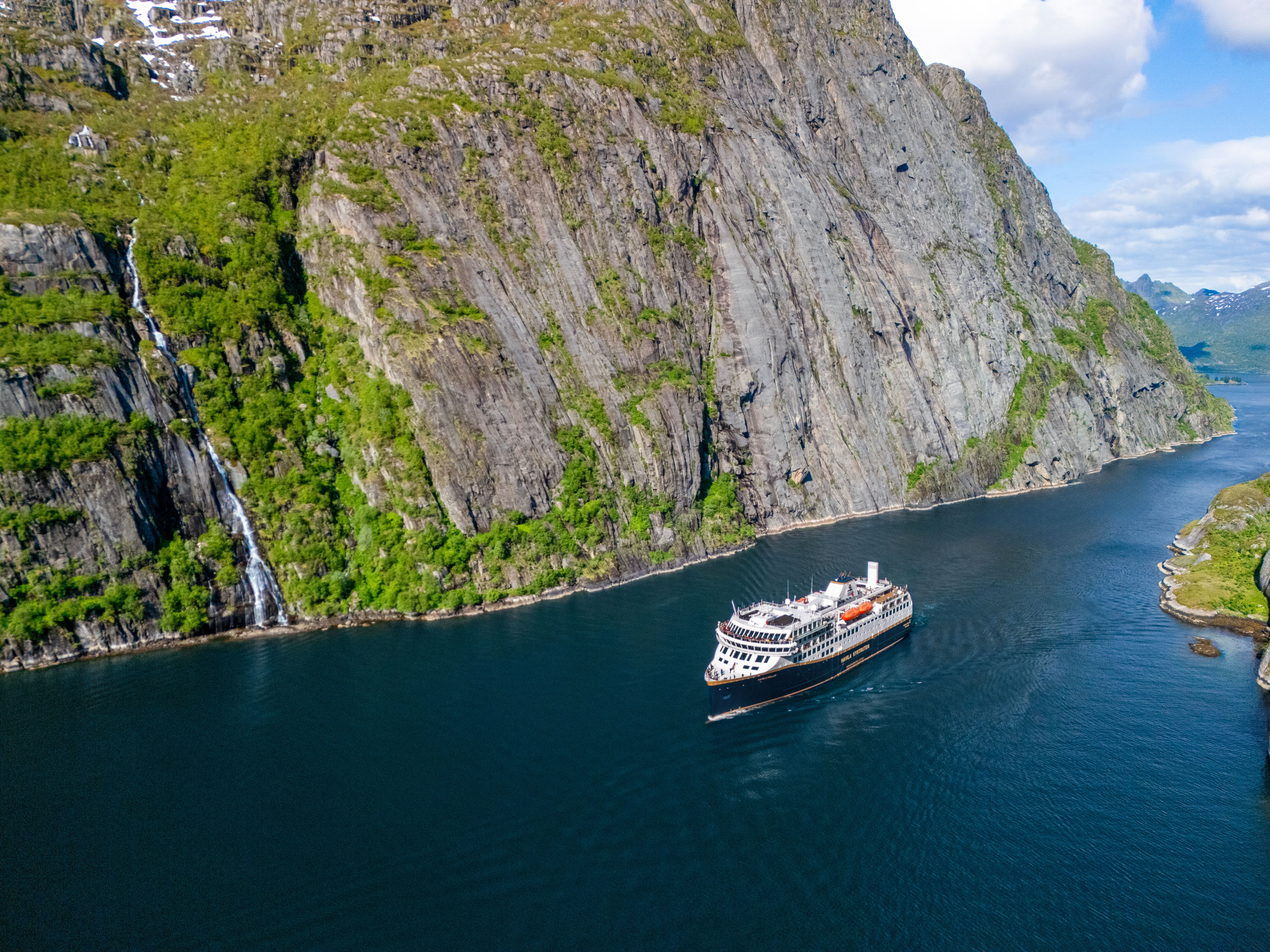 Schiff, das durch den Trollfjord fährt, unterhalb steiler Klippen und zerklüfteter Berge in Nordnorwegen.