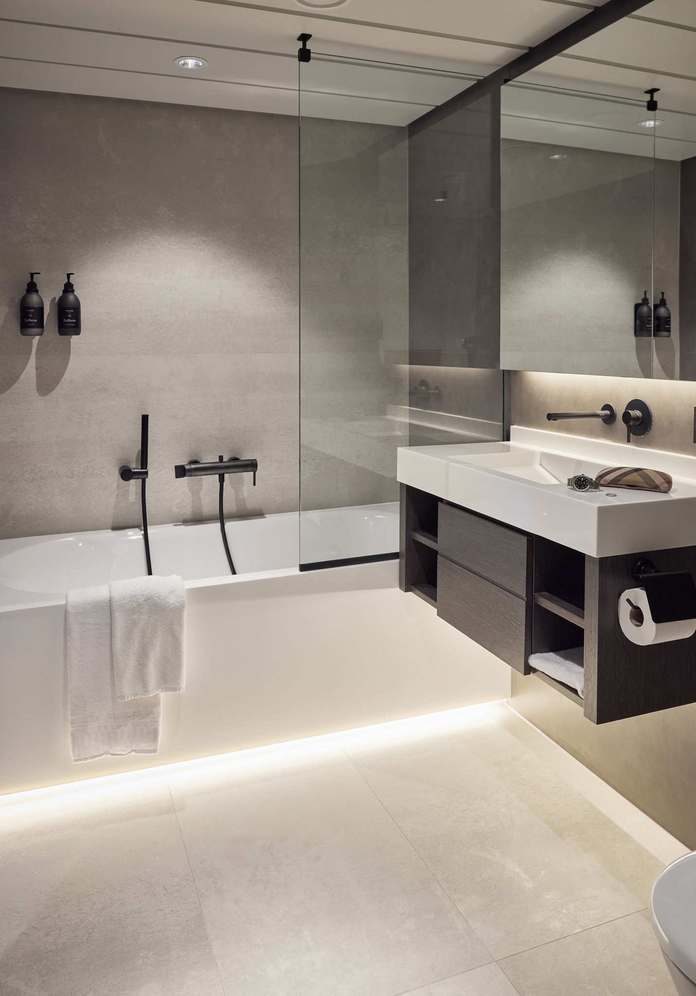 Modernes Badezimmer en suite mit Badewanne und Dusche, schwebendem Waschtisch, großem Spiegel, sanfter Beleuchtung und hochwertigen Oberflächen.