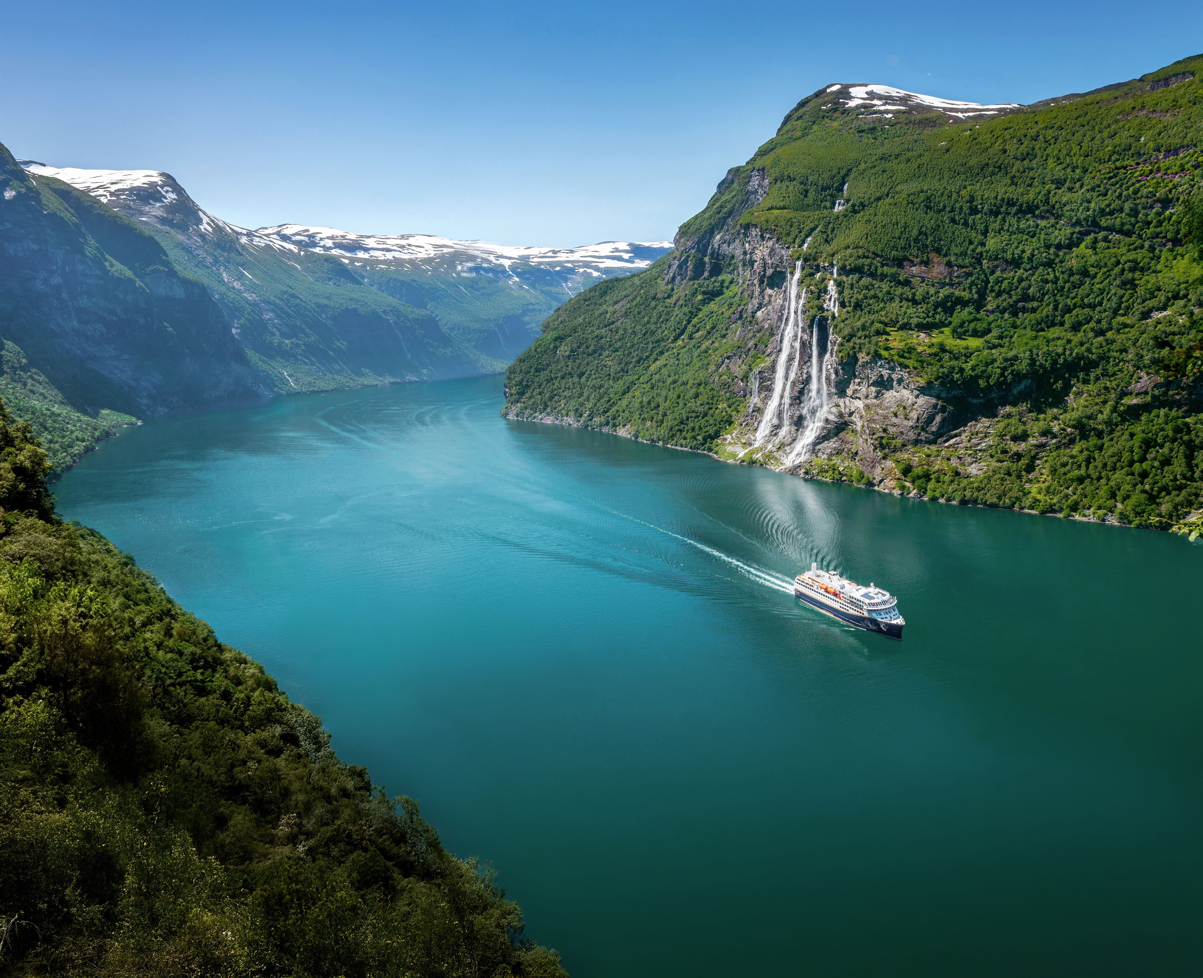 Havila Voyages sailing silently through Geirangerfjord during spring in Norway.