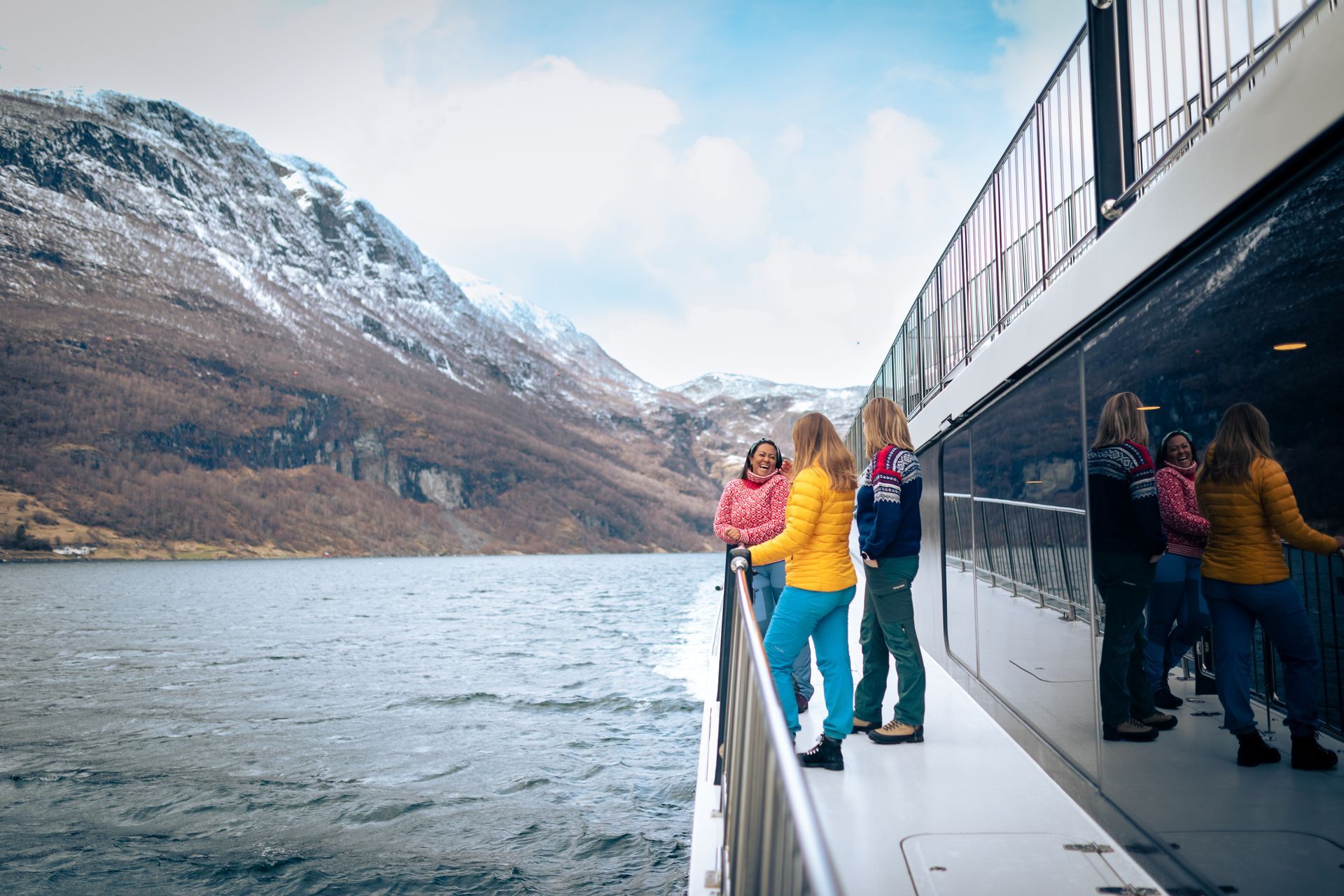 Reisende genießen eine Nærøyfjord-Kreuzfahrt, umgeben von schneebedeckten Bergen.