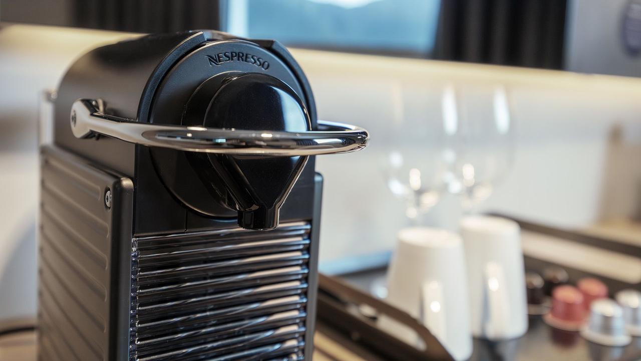 Nespresso-Kaffeestation in der Aft View Mini Suite mit einer hochwertigen Kaffeemaschine, Tassen, Gläsern und kostenlosen Kaffeekapseln.