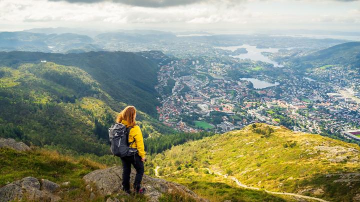 Wanderer genießt den Panoramablick vom Berg Ulriken über Bergen und die umliegenden Fjorde.