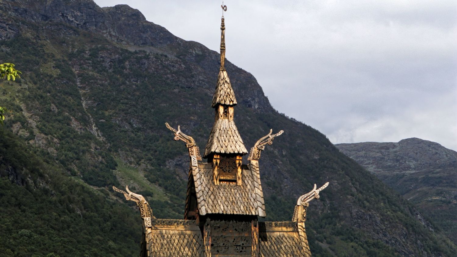 Die historische Stabkirche von Borgund in Norwegen, umgeben von Bergen und üppigem Grün, zeigt mittelalterliche Holzarchitektur und Handwerkskunst aus der Wikingerzeit.
