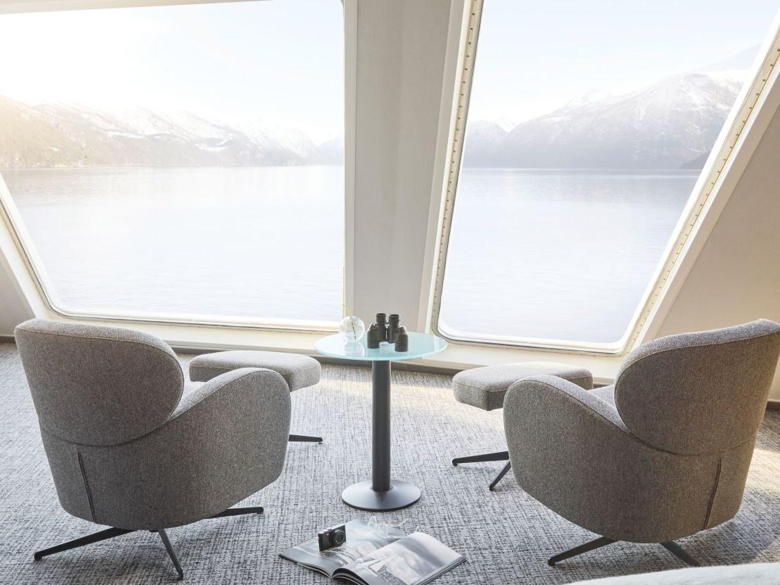 Sitteområde i Panoramic Corner Mini Suite med vinduer fra gulv til tak og utsikt over den norske kysten.