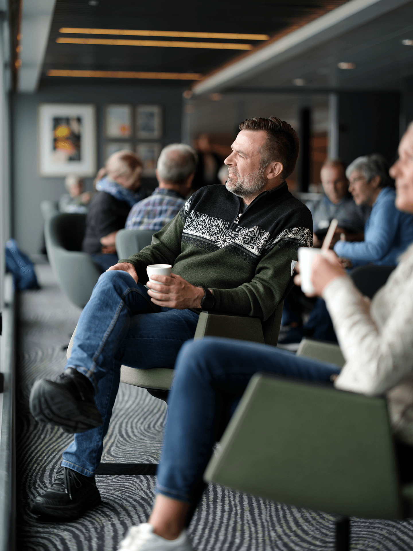 Gjester som slapper av med varm drikke i lenestoler i skipets salong