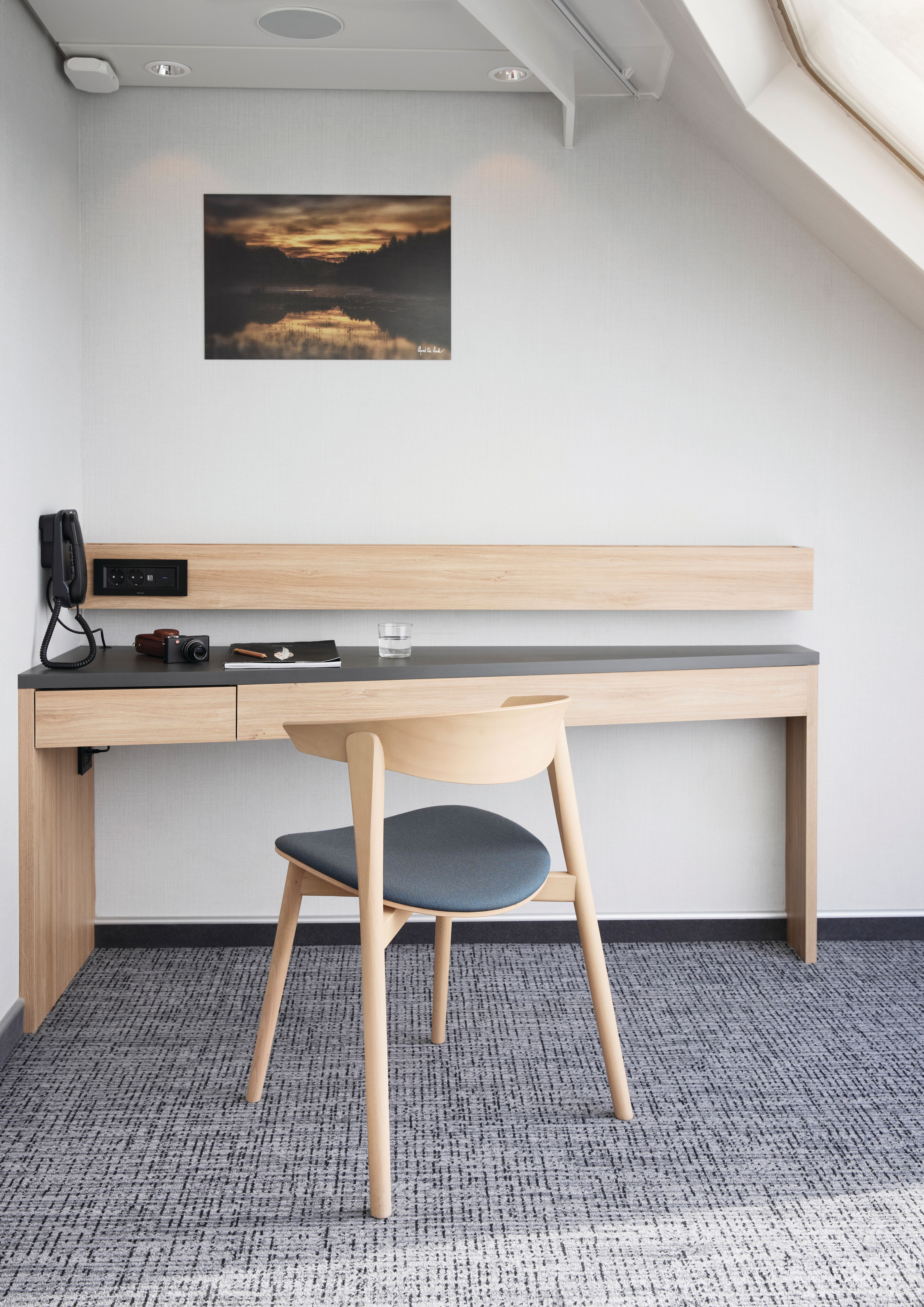 Arbeidsområde i Panoramic Corner Mini Suite med romslig skrivebord, stol, telefon, stikkontakter og naturlig lys fra suitenes panoramavindu.