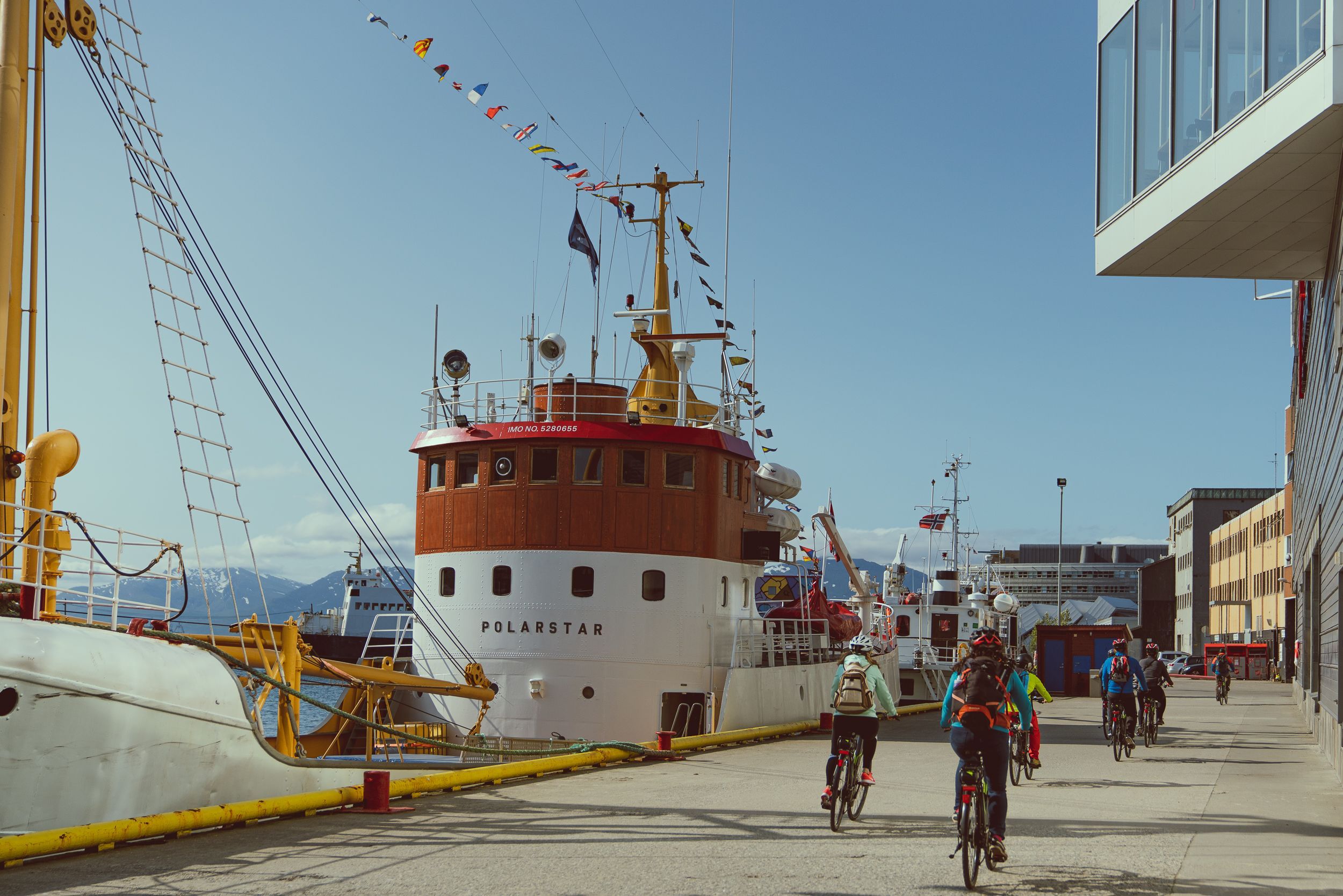 Gjester som sykler langs havnepromenaden i Tromsø på en guidet elsykkeltur forbi den historiske havna.
