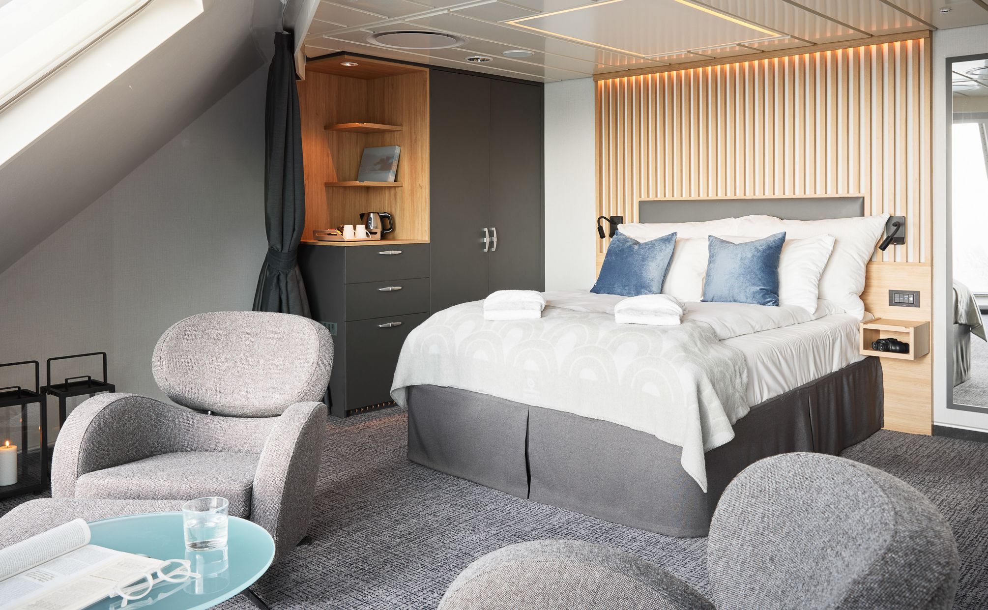 Panoramisk hjørneminisuite med king-size-seng, hjørnevinduer fra gulv til tak, lounge-sittegruppe og enestående panoramautsikt over havet.
