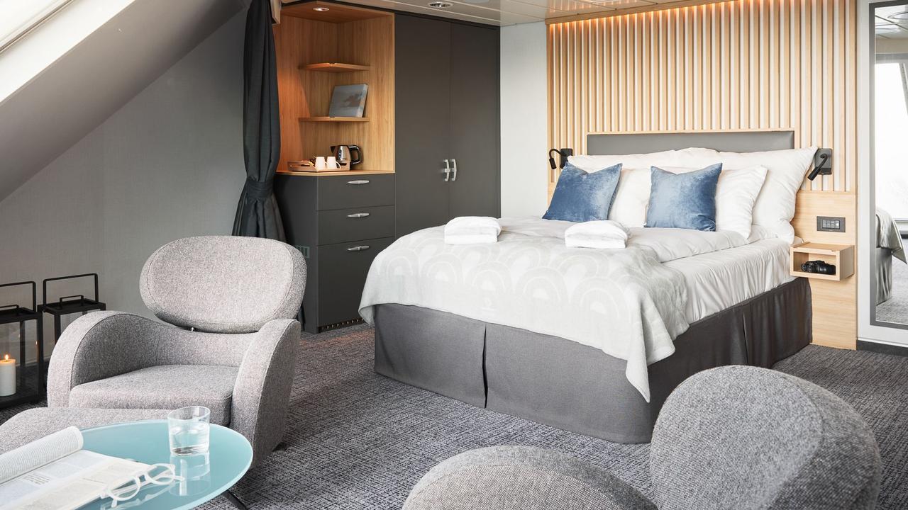Panorama-Ecksuite Mini mit Kingsize-Bett, raumhohen Eckfenstern, Lounge-Sitzbereich und atemberaubendem Panoramablick auf das Meer.
