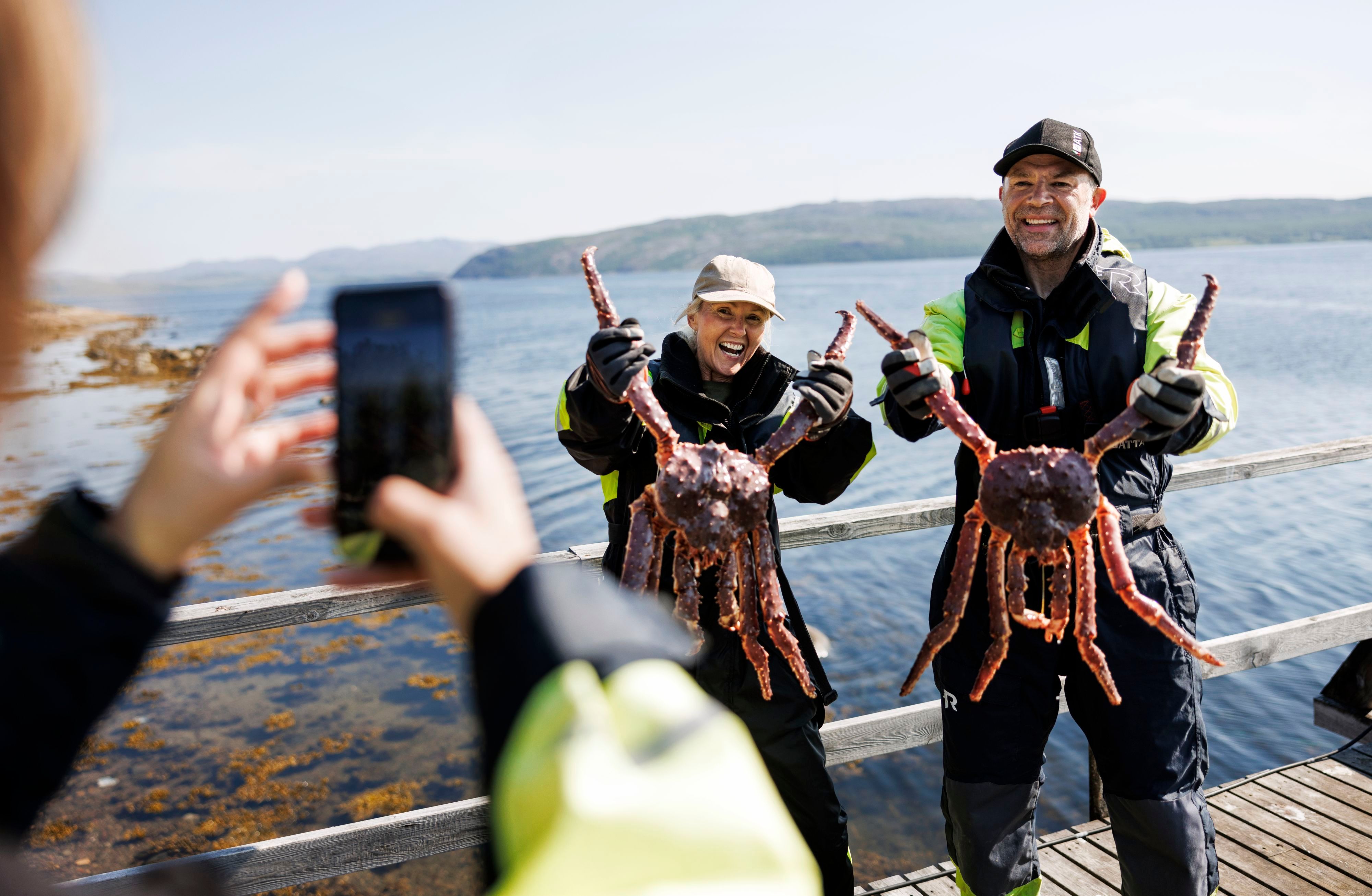 Two people holding king crabs on a Norway excursion with Havila