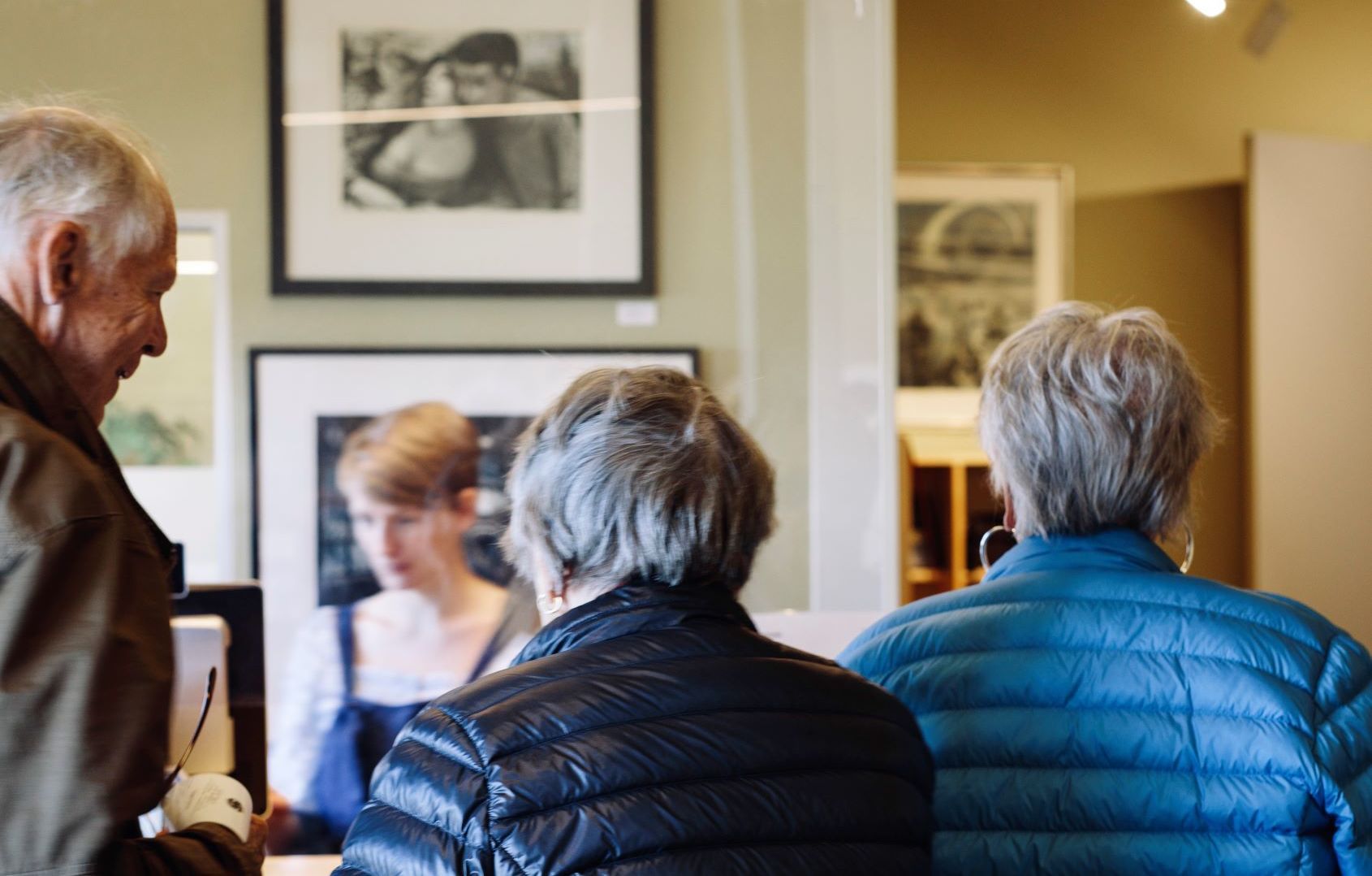 Besøkende som ser på innrammet svart-hvitt-kunst under et galleri­besøk i Lofoten, Norge