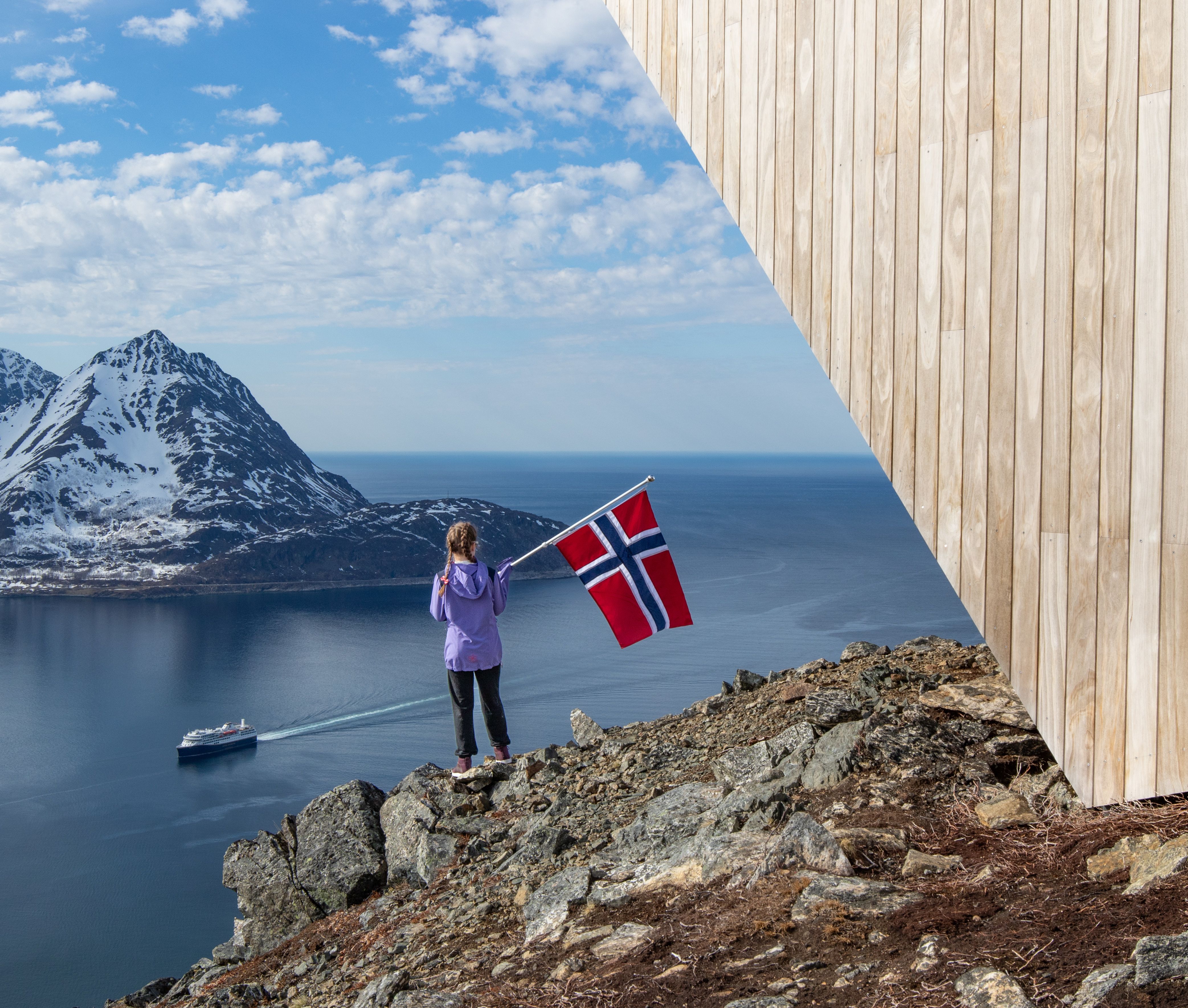 Barn som vinker med det norske flagget fra en fjellside mens et skip seiler gjennom fjorden nedenfor