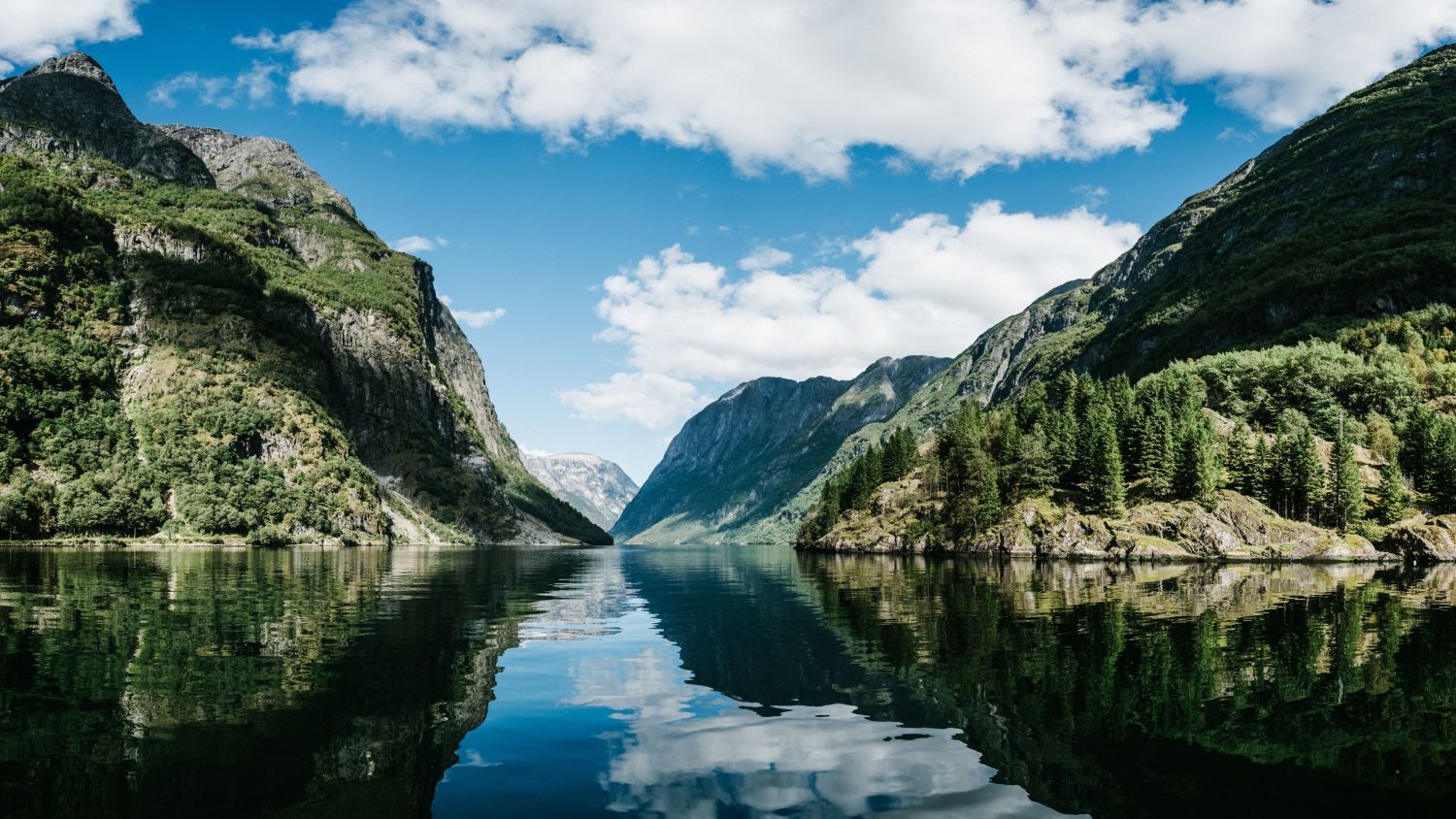 Ruhige Wasser des Nærøyfjords spiegeln die hoch aufragenden Berge, üppigen Wälder und den blauen Himmel im UNESCO-Weltnaturerbe-Fjord Westnorwegens wider.
