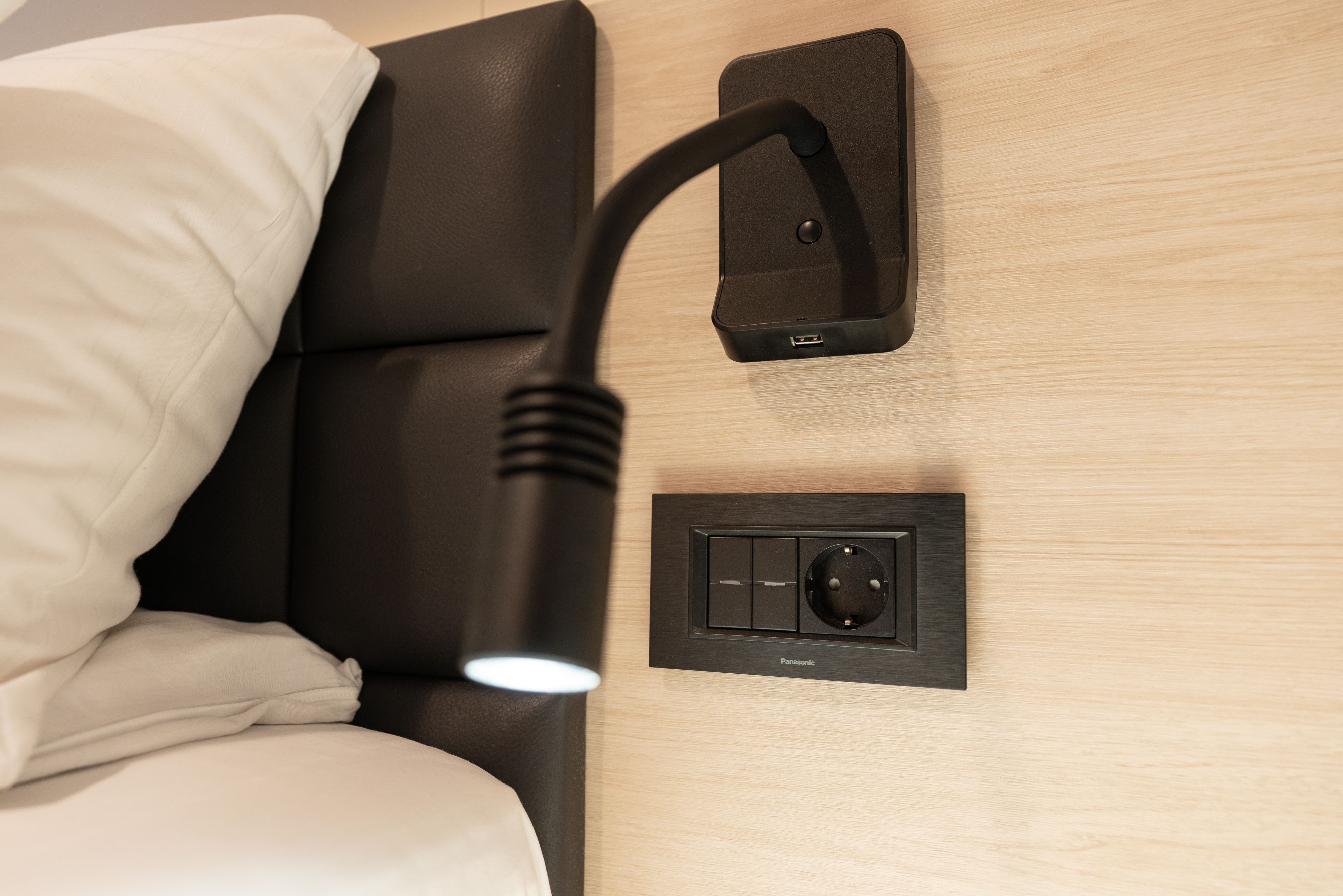 Seaview Superior King Kreuzfahrtkabine mit Nachttisch-Leselampe, USB-Ladeanschluss, Steckdose und praktischen Bedienelementen am Bett.