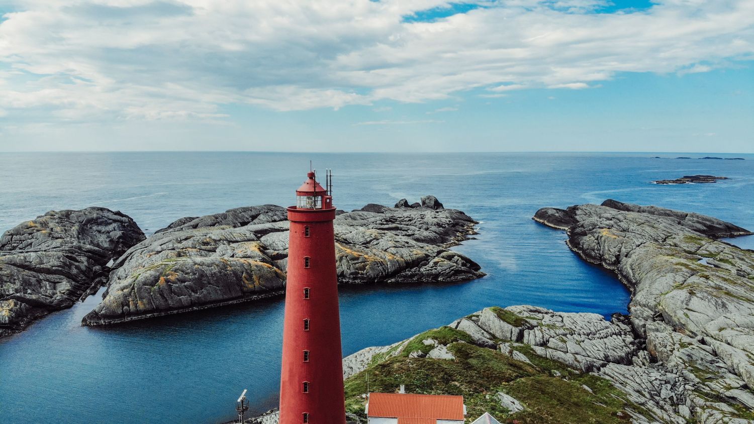 Utvær Lighthouse on Norway's westernmost islands, featuring the iconic red lighthouse overlooking rugged coastal rocks and the open Norwegian Sea. Photo by Lillian Herland