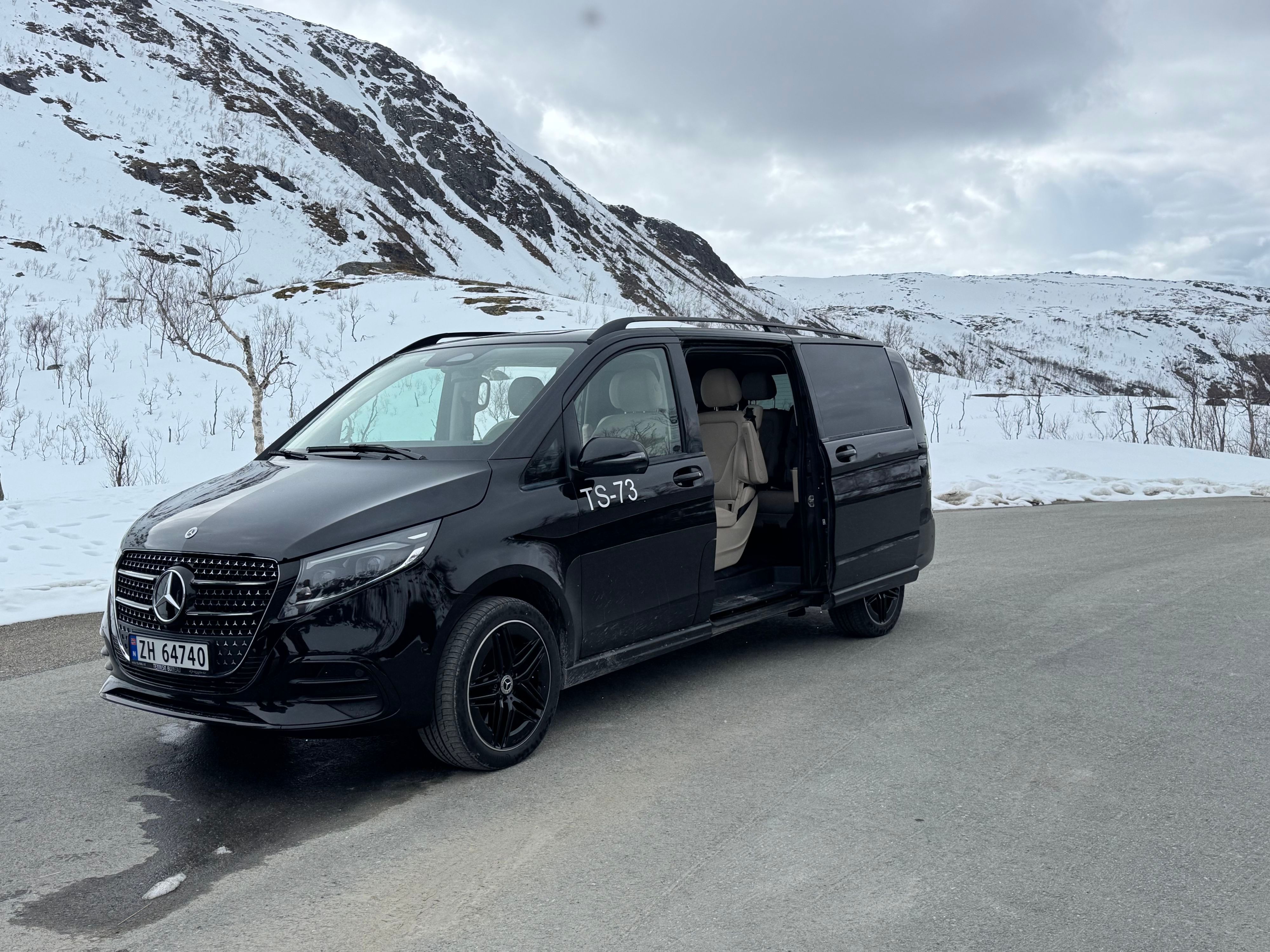 Komfortabelt turbiler parkert langs Nasjonal turistveg Senja, omgitt av snødekte fjell og arktiske landskap i Nord-Norge.