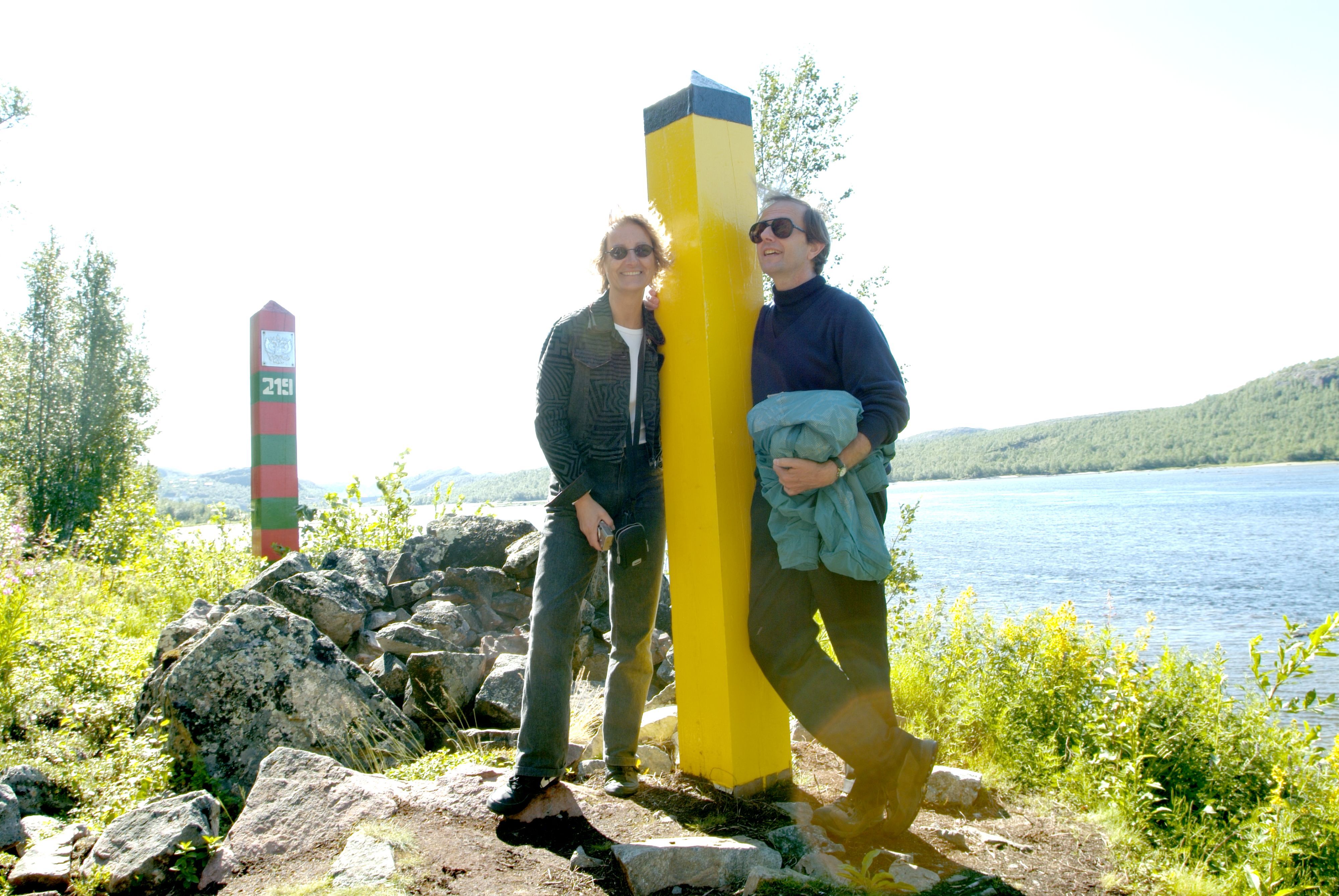 Visitors standing beside the Norway–Russia border marker near Kirkenes in Northern Norway.