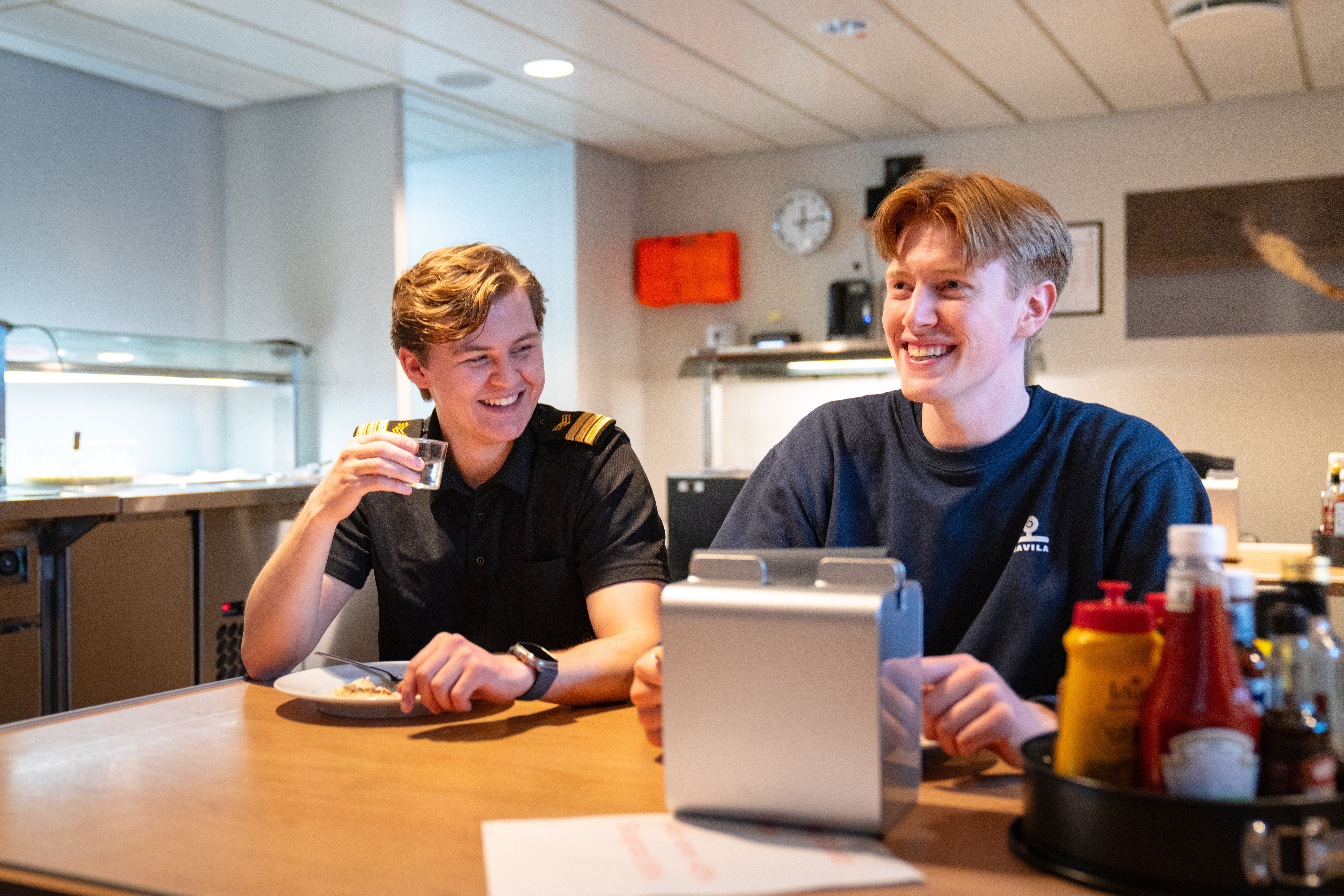Havila-mannskap smiler og spiser mat