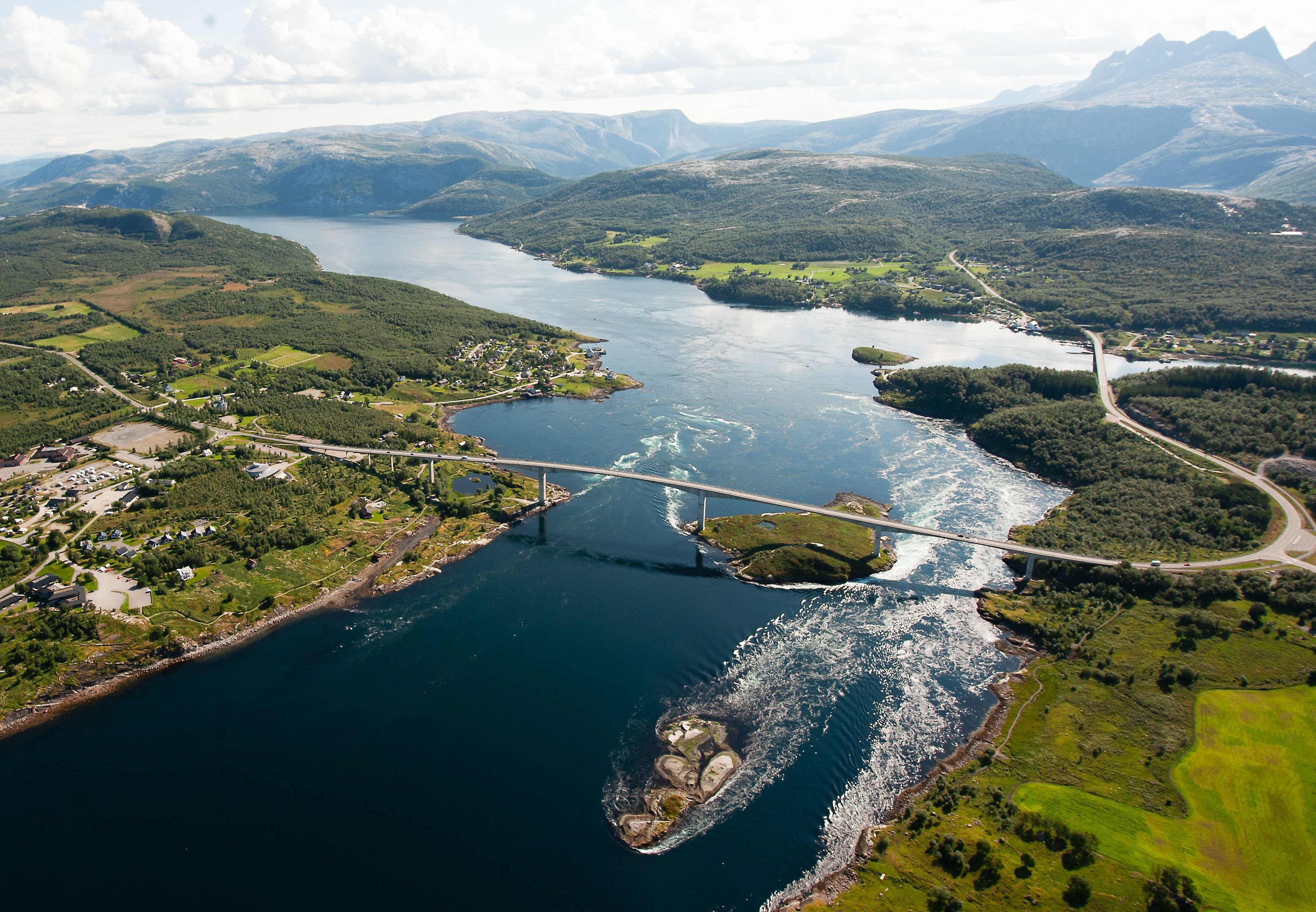 Sommerlig flyfoto av Saltstraumen og broen mellom grønne åser og fjell nær Bodø i Norge