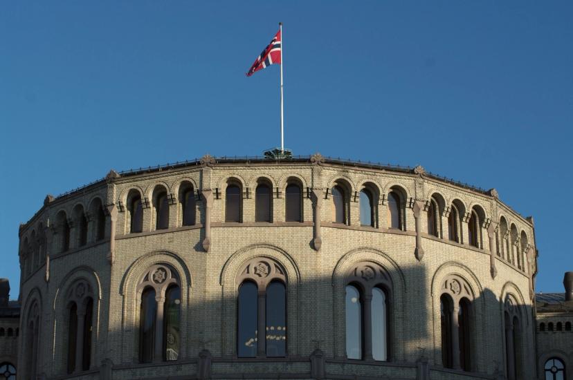 Stortingets runde hovedfløy med det norske flagget mot blå himmel