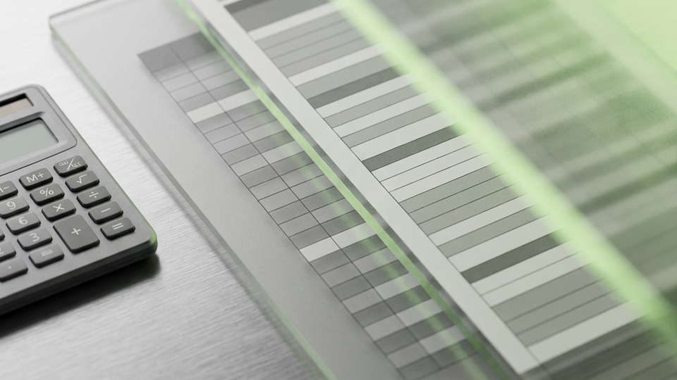 Aligned translucent sheets beside a calculator on a desktop.