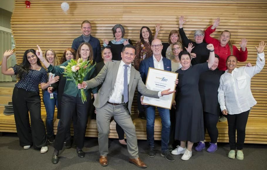 Glad gruppe, der fejrer med blomster og et diplom