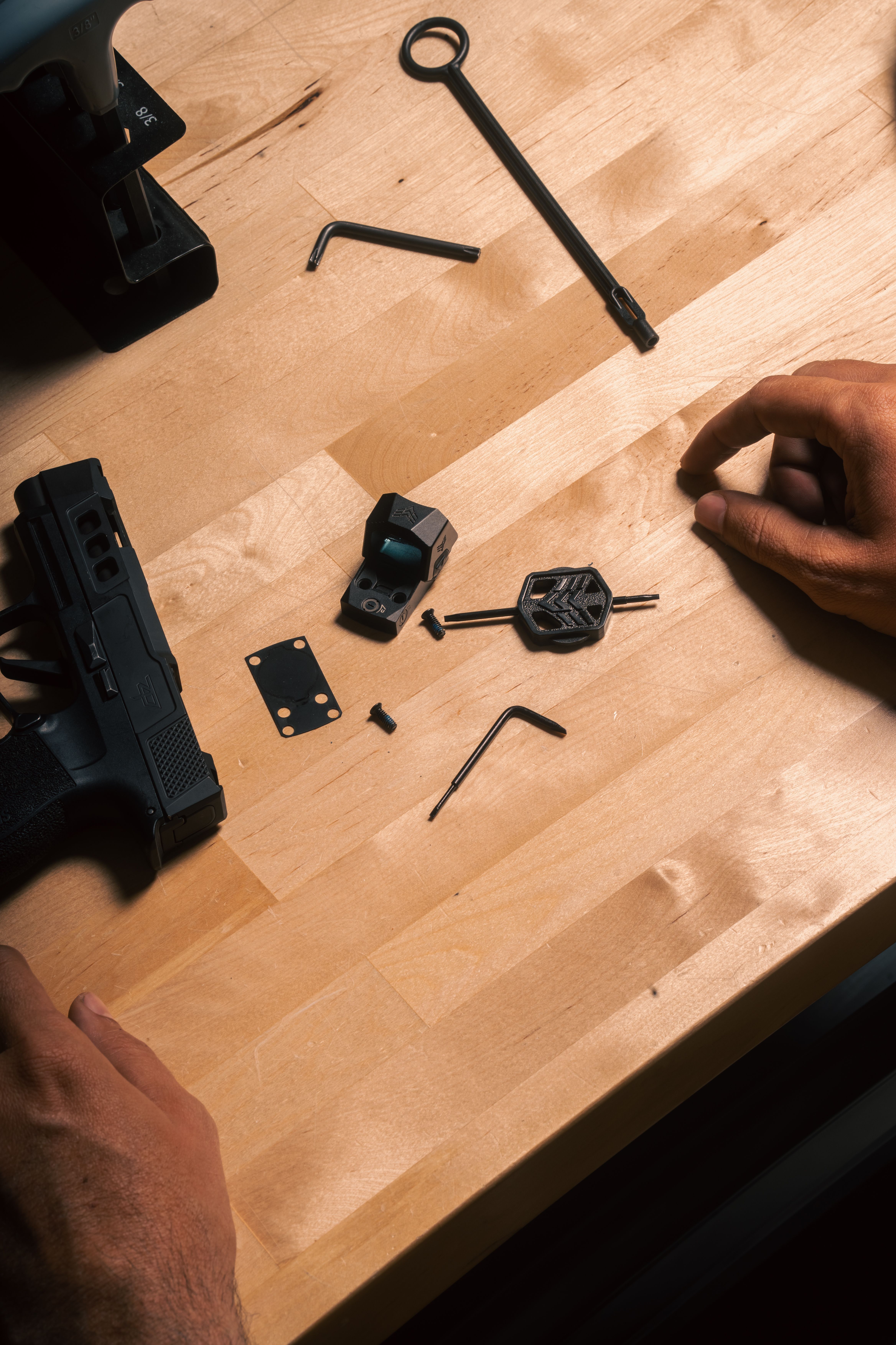 Swampfox Sentinel II with mounting plates, screws, and parts laid out on a workbench next to a Sig P365