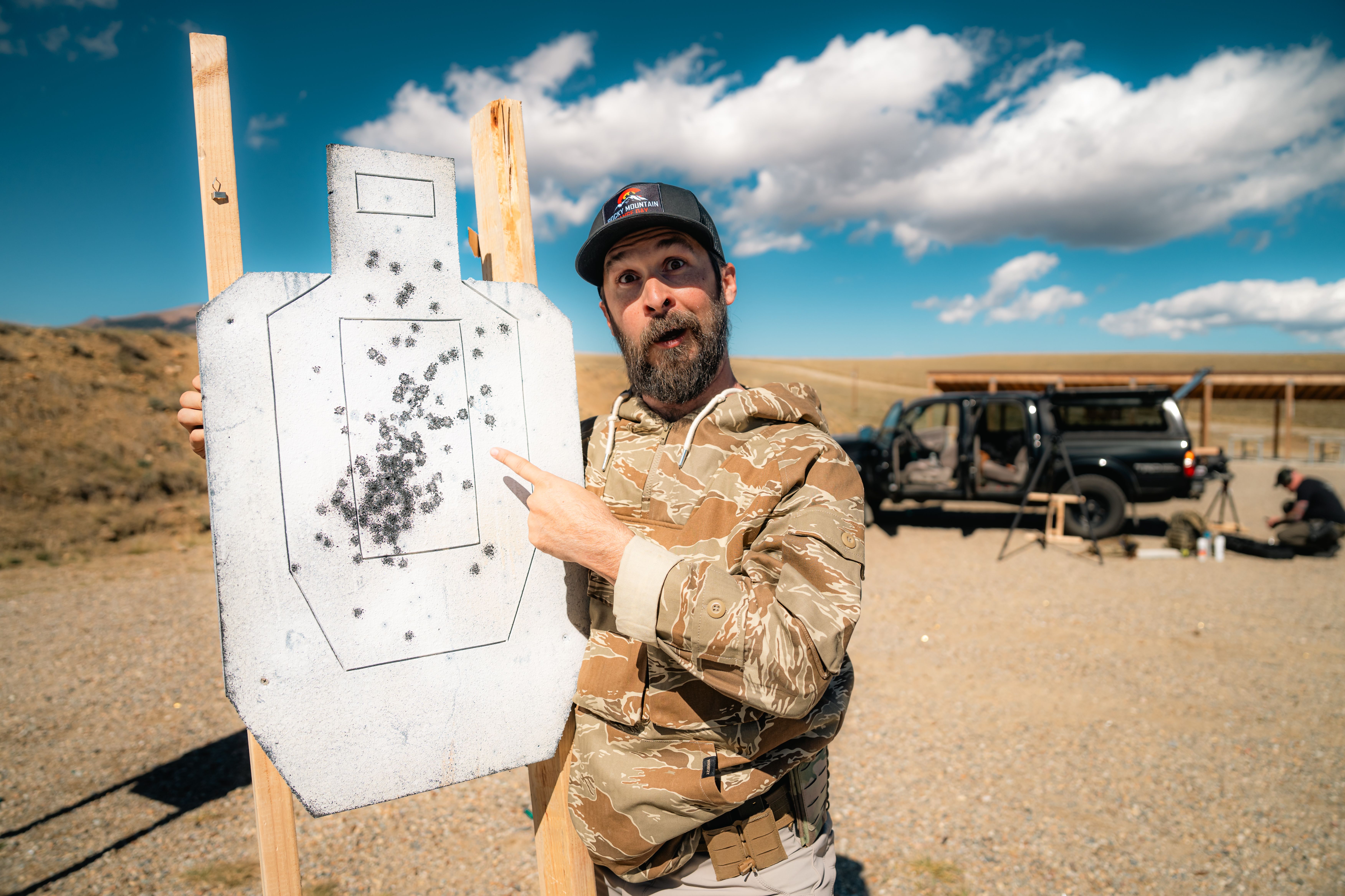 Shooter standing next to an IPSC paper target reviewing hits after a USPSA stage