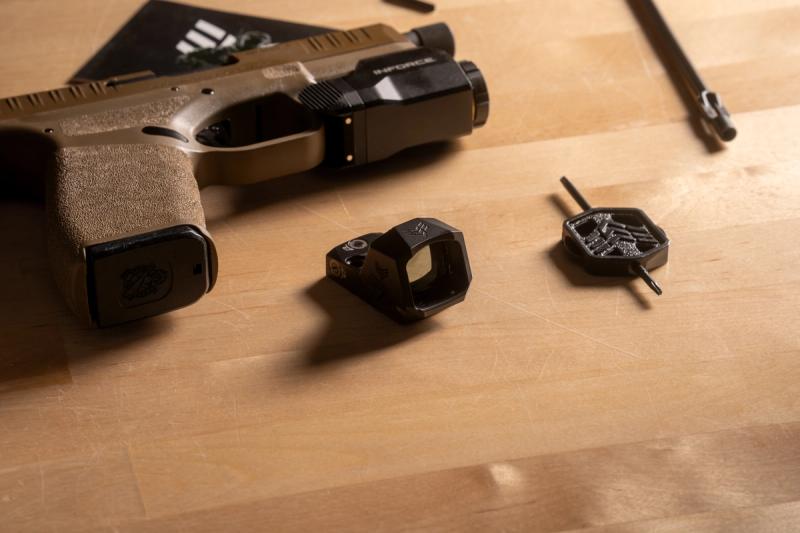 Swampfox Sentinel II micro red dot on a workbench next to an FDE Springfield Hellcat Pro and the Swampfox adjustment tool