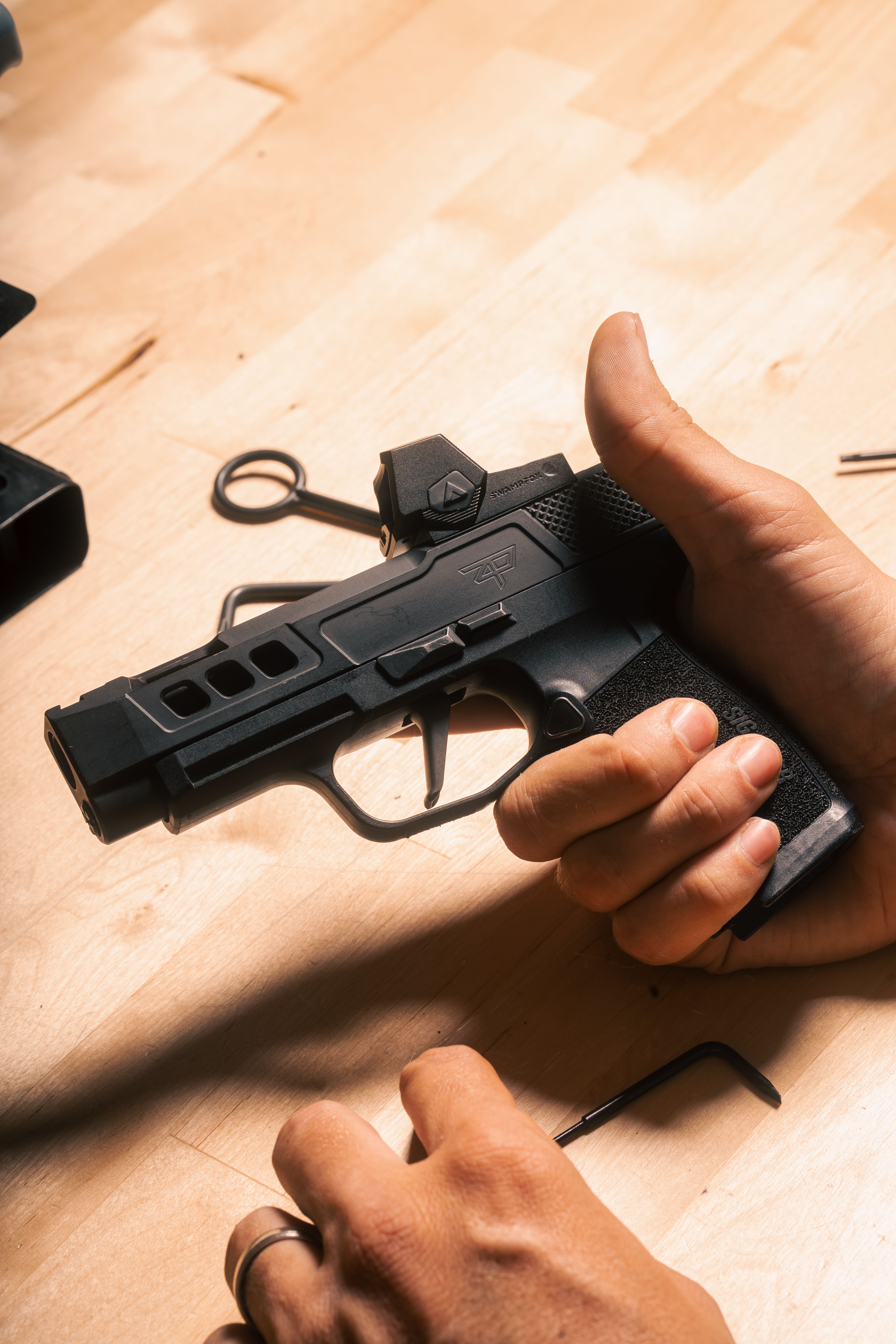 Sig P365 in hand with a Swampfox Sentinel II red dot mounted on the slide