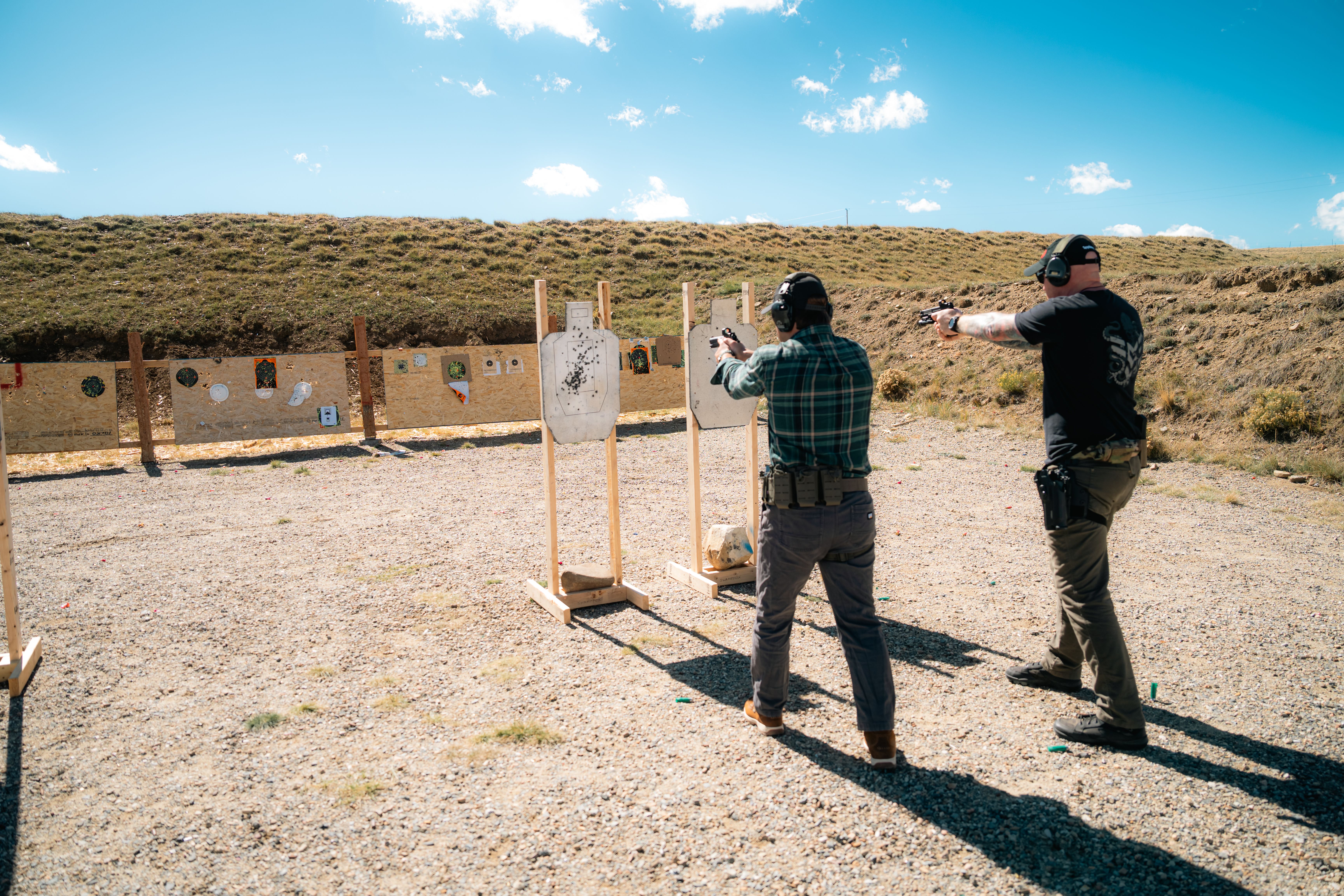 Two competitors shooting side by side at IPSC targets on a USPSA range