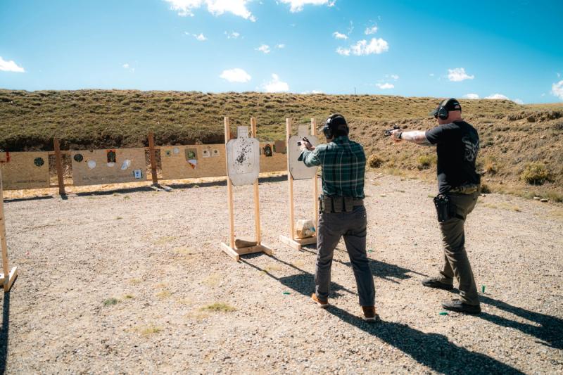 Two competitors shooting side by side at IPSC targets on a USPSA range