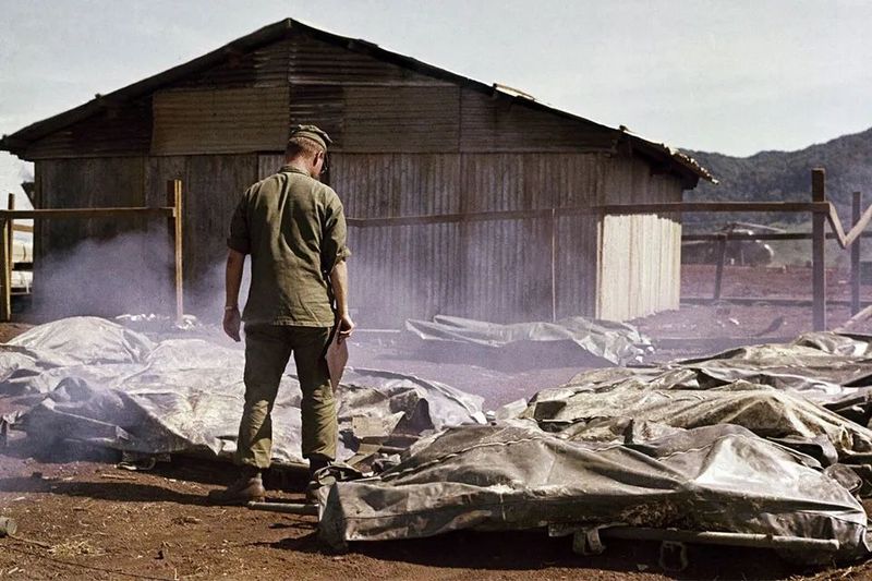 U.S. soldier standing over fallen soldiers on the Vietnam battlefield