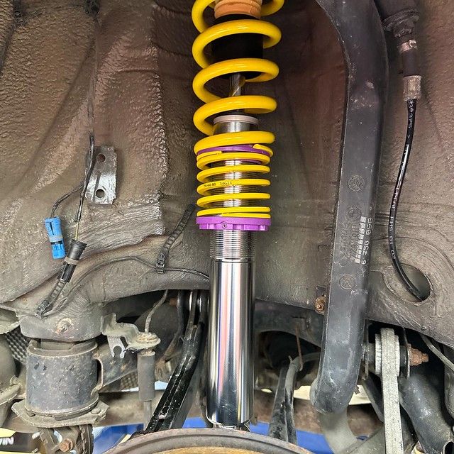 Close-up of a freshly installed KW coilover suspension with yellow springs and purple adjusters on a BMW E38 7 Series.